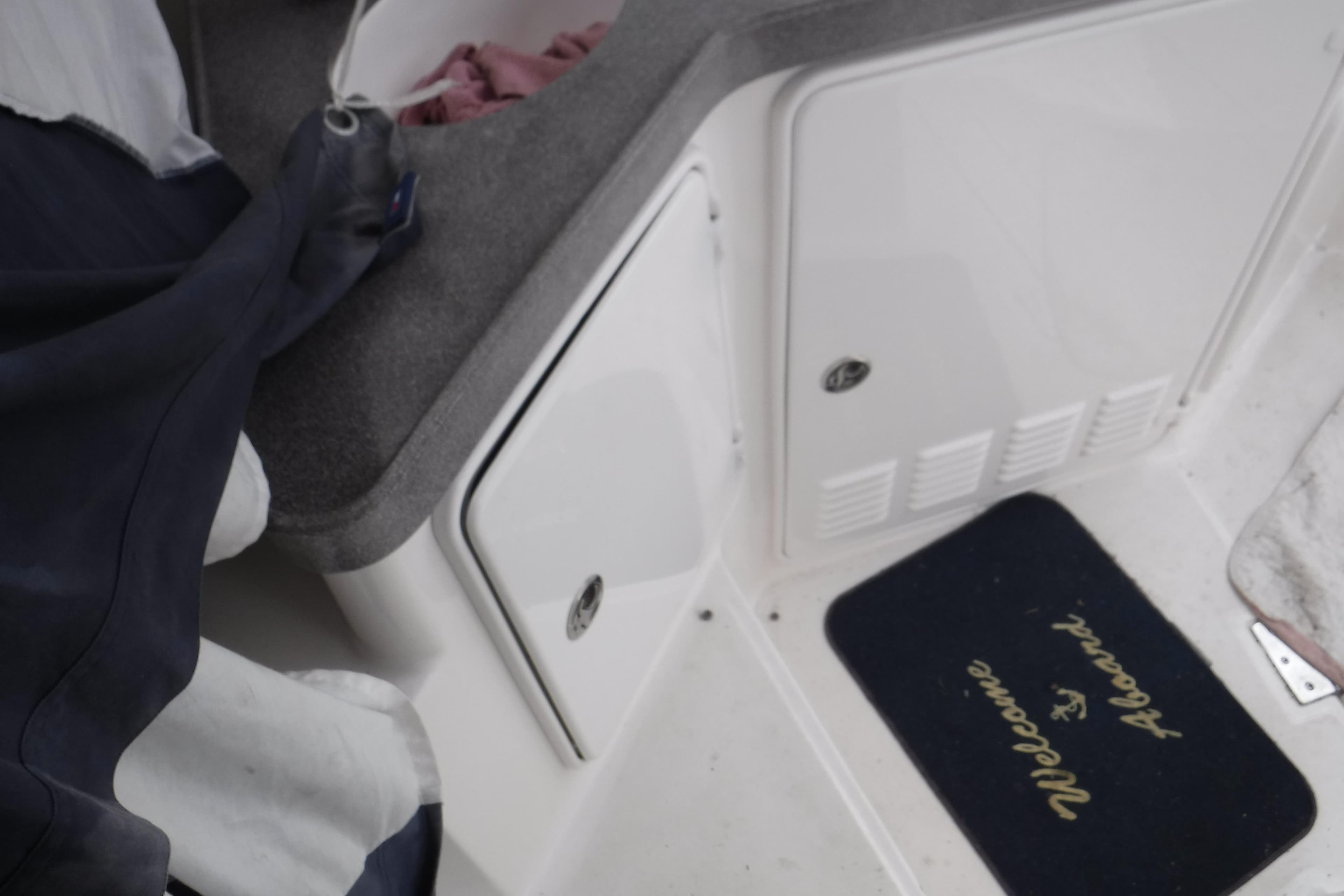 2006 Regal Commodore 3560 IO boat interior with "Welcome Aboard" mat and storage compartments.