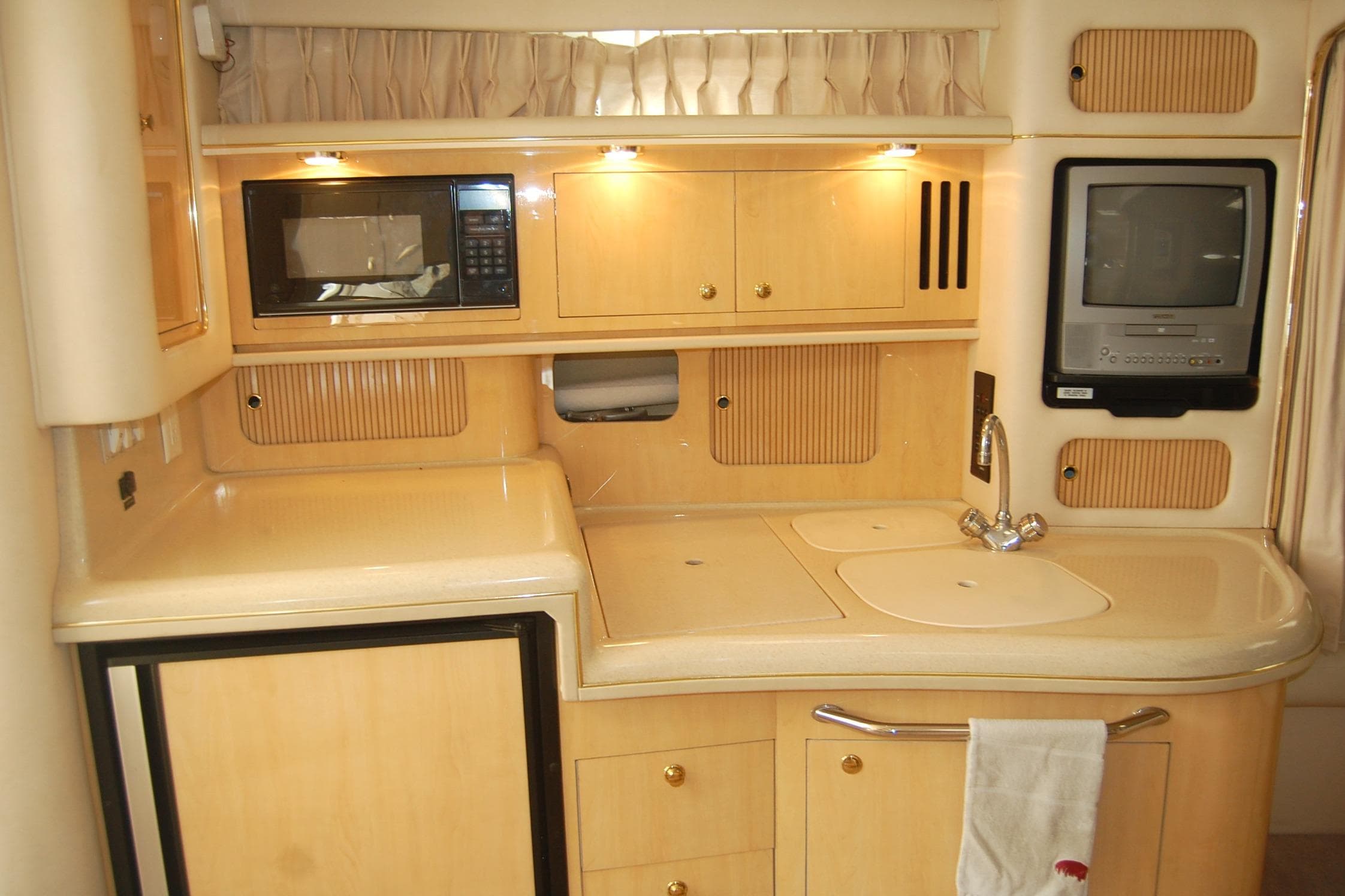 Interior of 2000 Sea Ray 340 Sundancer yacht with kitchenette, microwave, and TV.