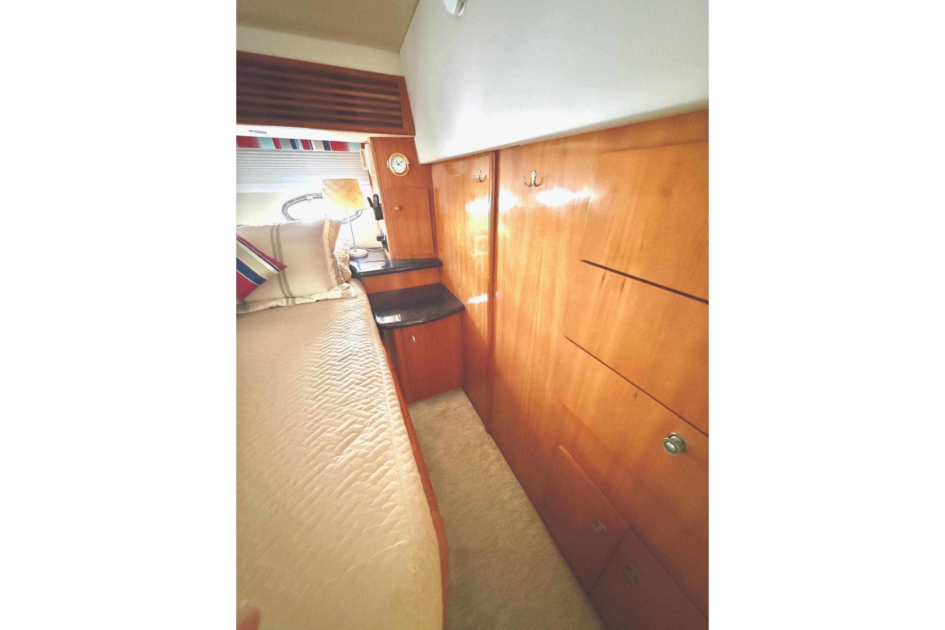 Interior of 2001 Carver 444 Cockpit Motor Yacht with wooden cabinetry and cozy bedding.