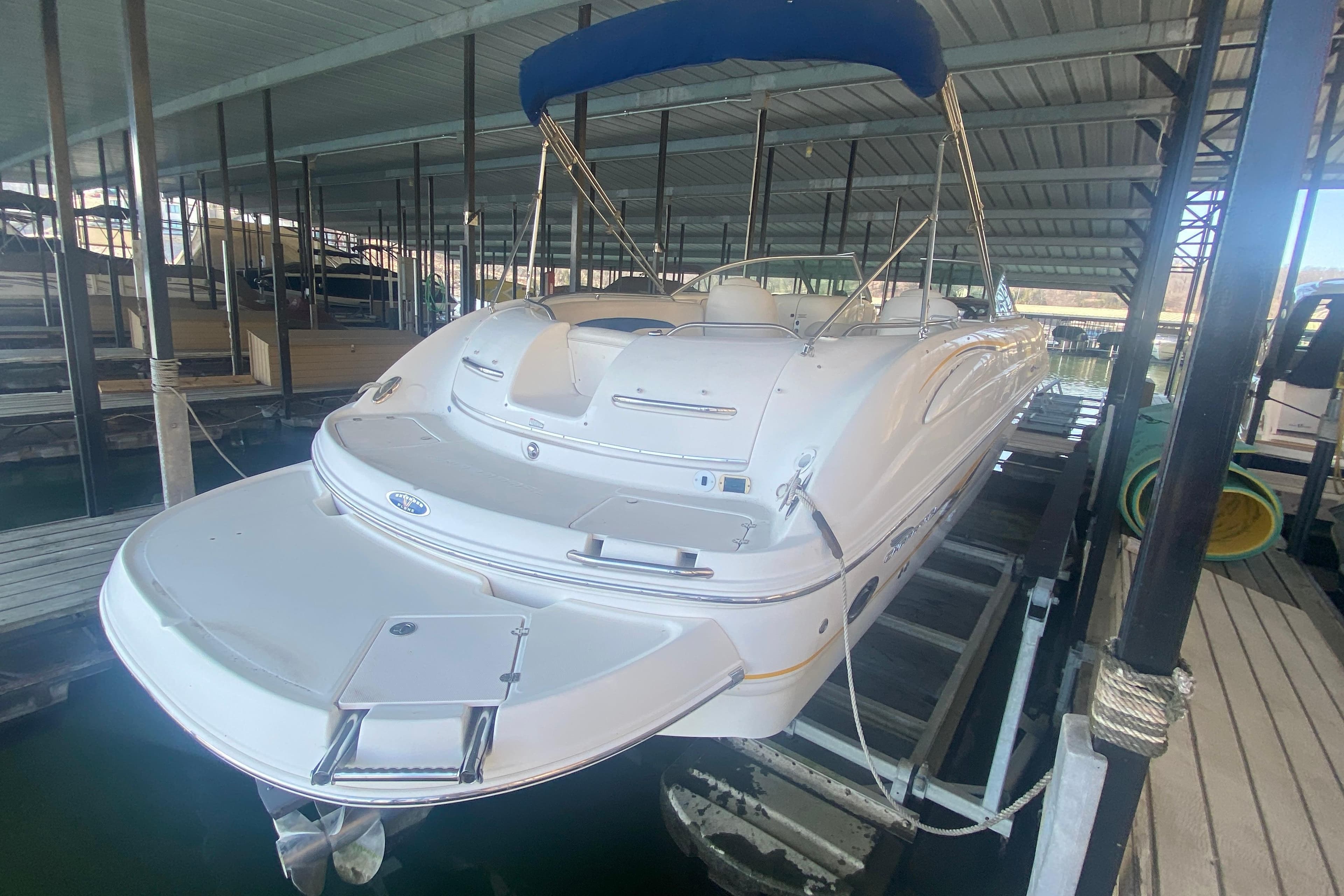 2003 Chaparral Sunesta 263 boat docked under a covered marina with blue canopy.
