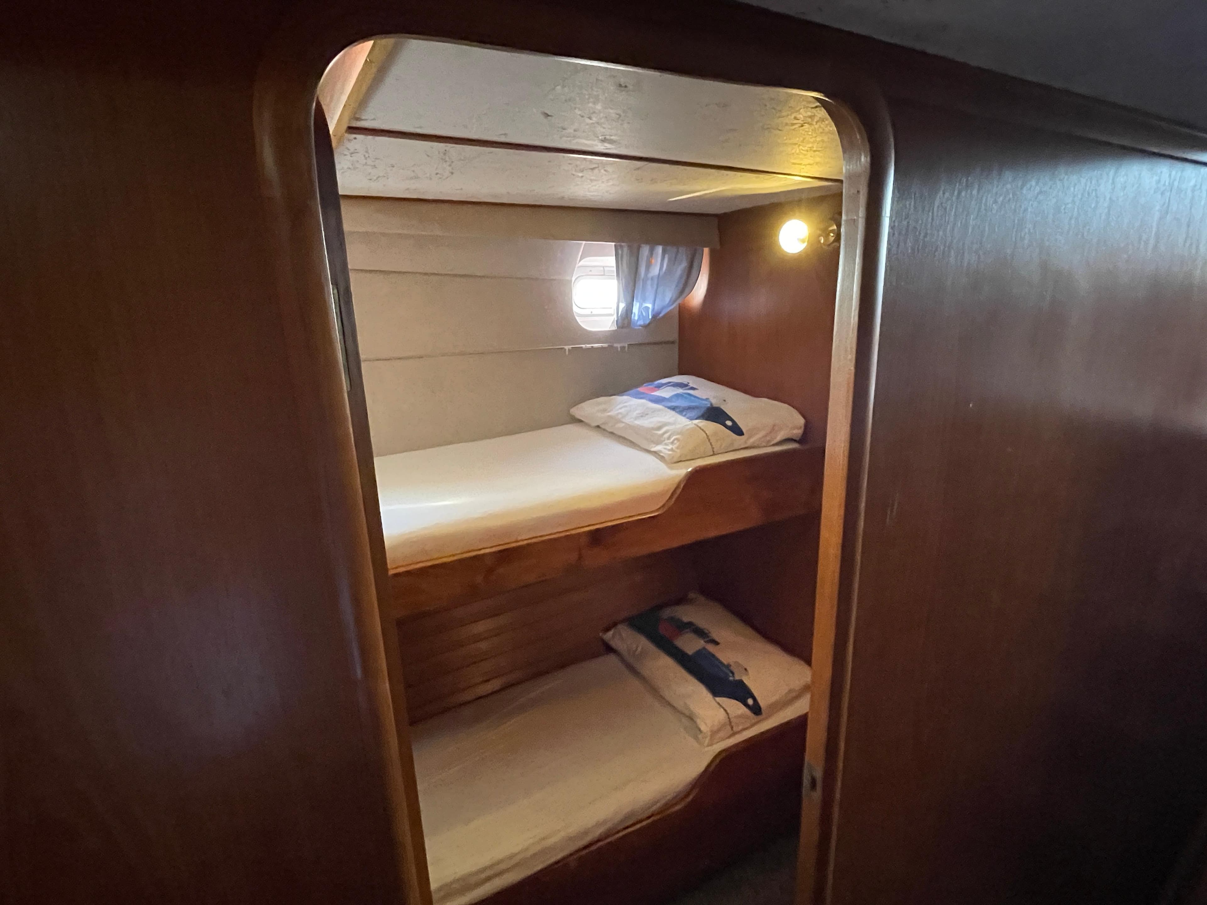 Bunk beds in 1986 Moody Trawler 50 cabin with wooden interior and porthole.