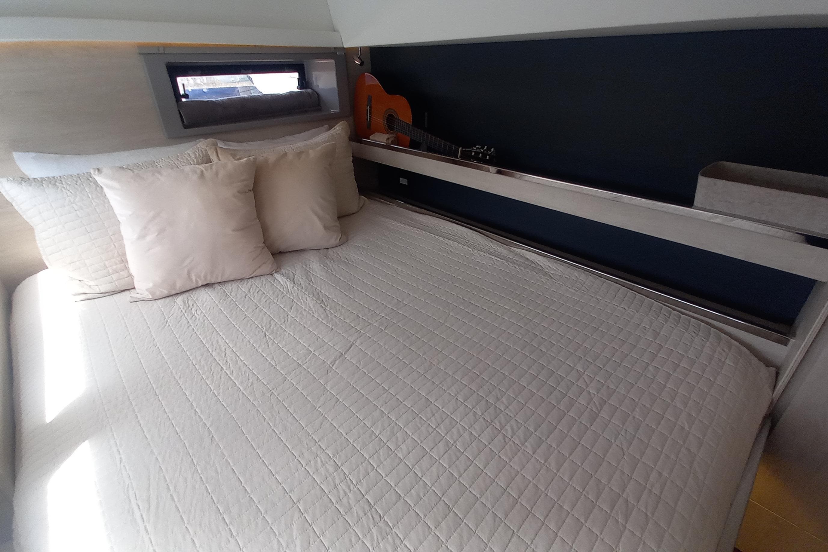 Cozy bedroom in 2019 Leopard 45 yacht with guitar and pillows.