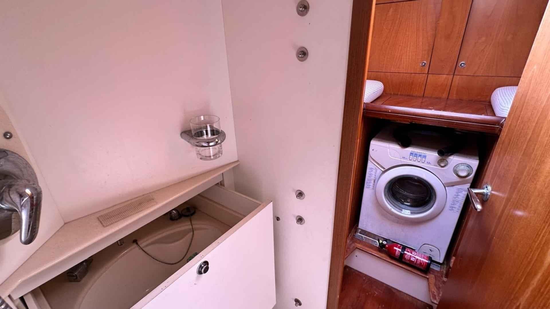 Laundry area with washing machine and storage in a 2004 Moody 64 yacht.
