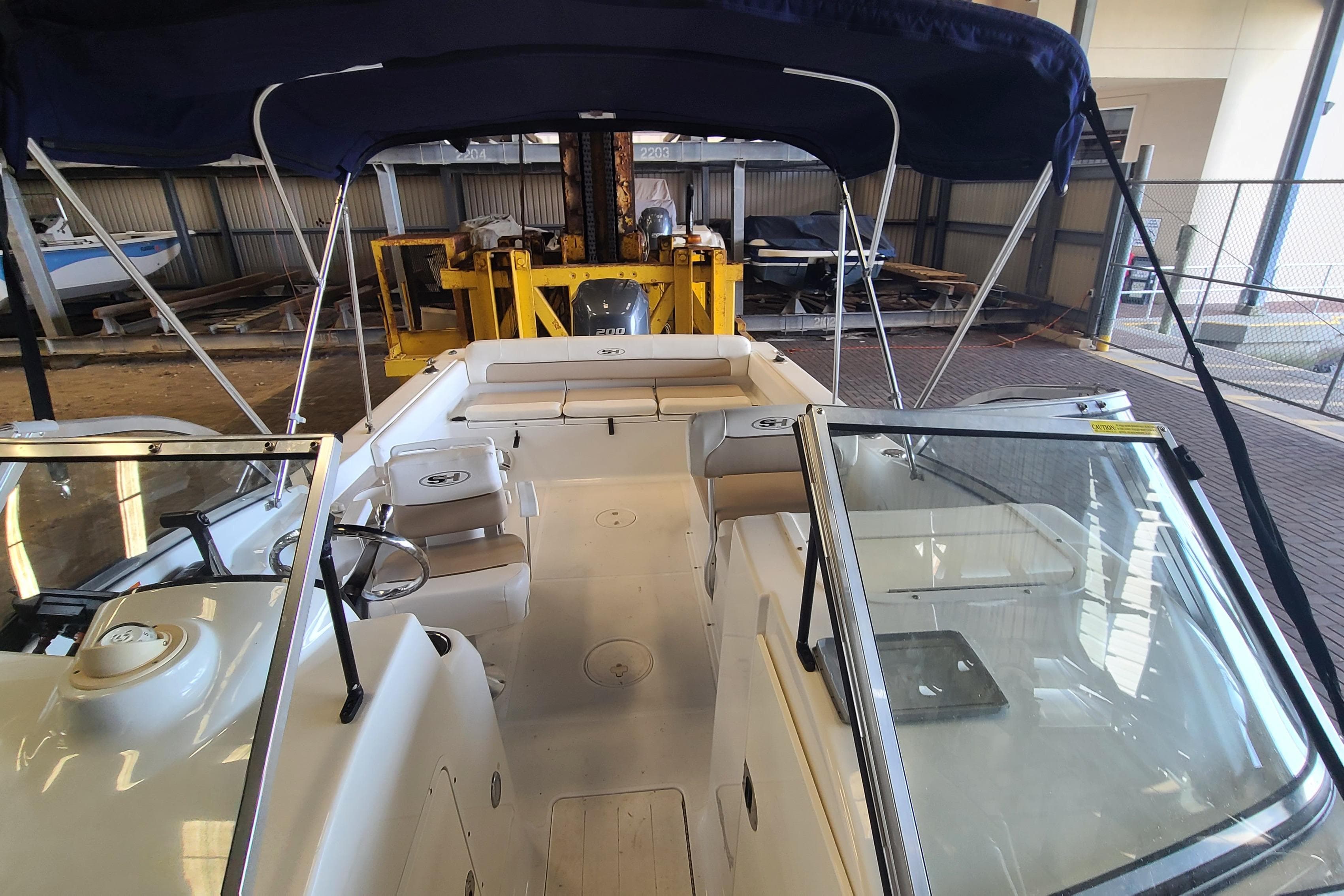 2013 Sea Hunt Escape 234 LE boat interior with seating and steering wheel in a storage facility.