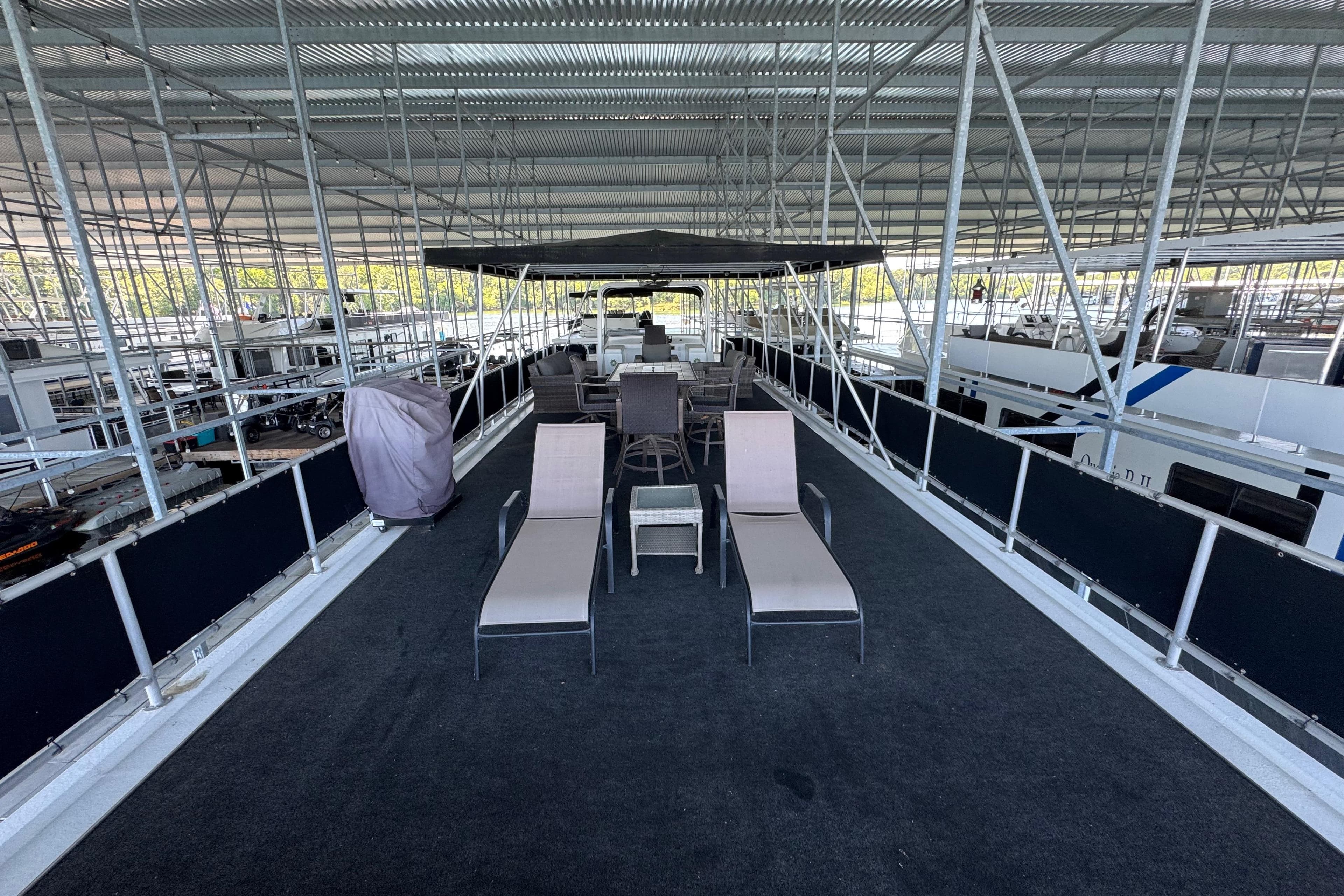 Rooftop deck of 2004 Starlite 65x16 houseboat with lounge chairs and seating area.