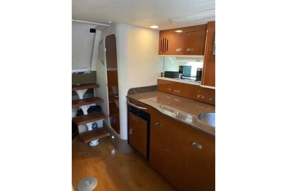 Interior of 2012 Sea Ray 350 Sundancer yacht, featuring a modern kitchen and wooden stairs.