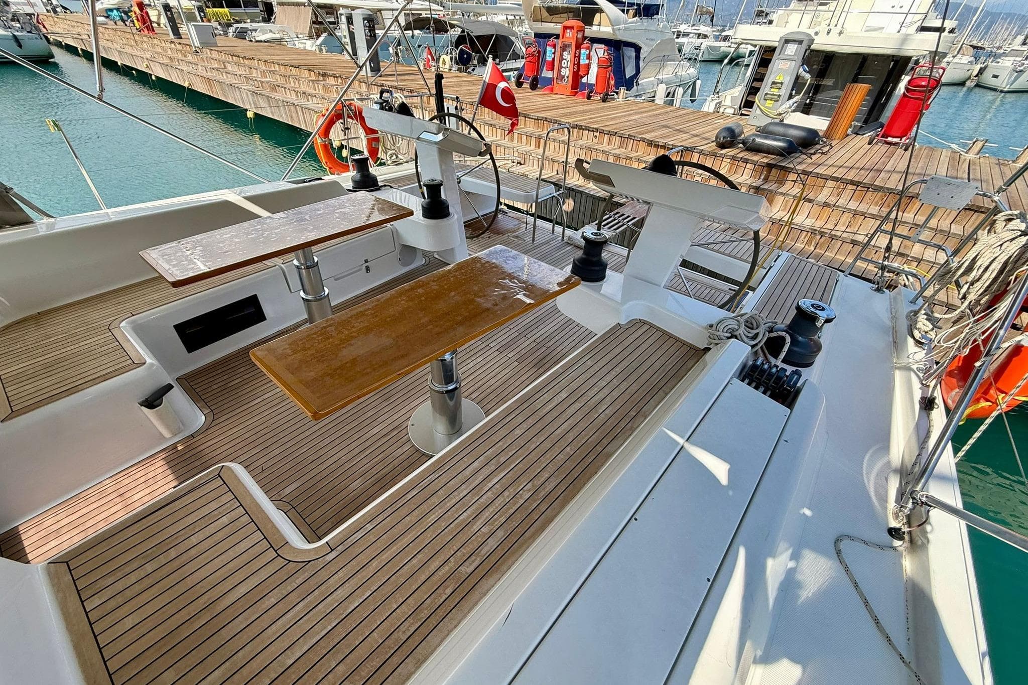 2023 Hanse 548 yacht cockpit with dual steering wheels and wooden seating, docked at marina.
