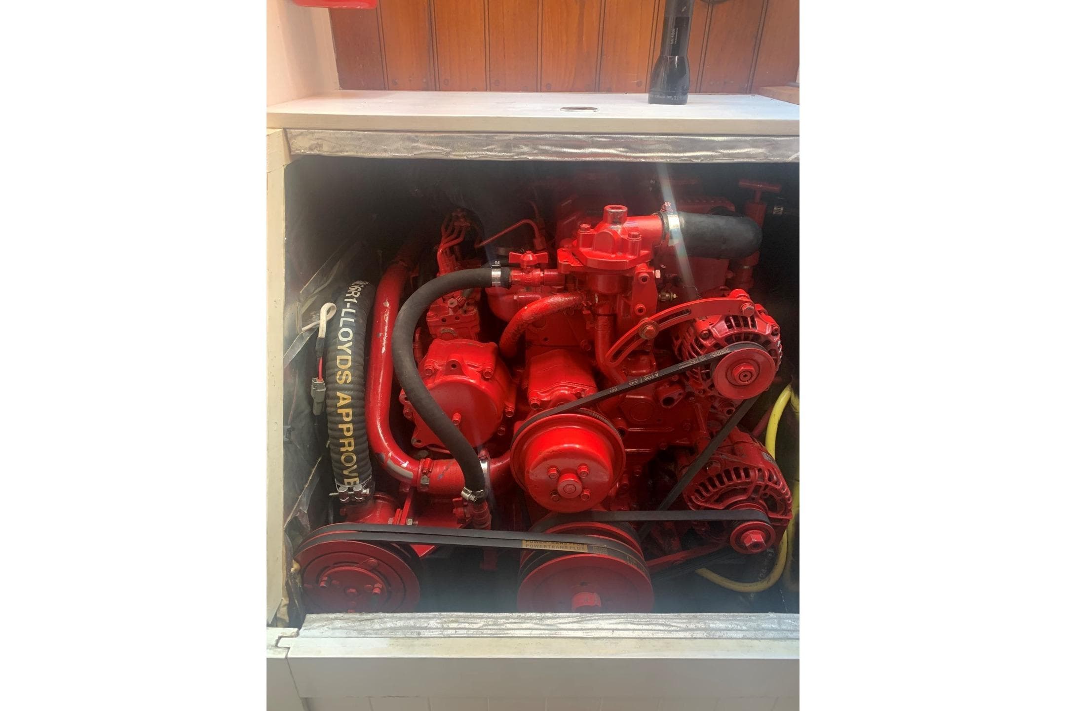 Red engine inside 1899 Classic Bristol Pilot Cutter, showcasing mechanical components.