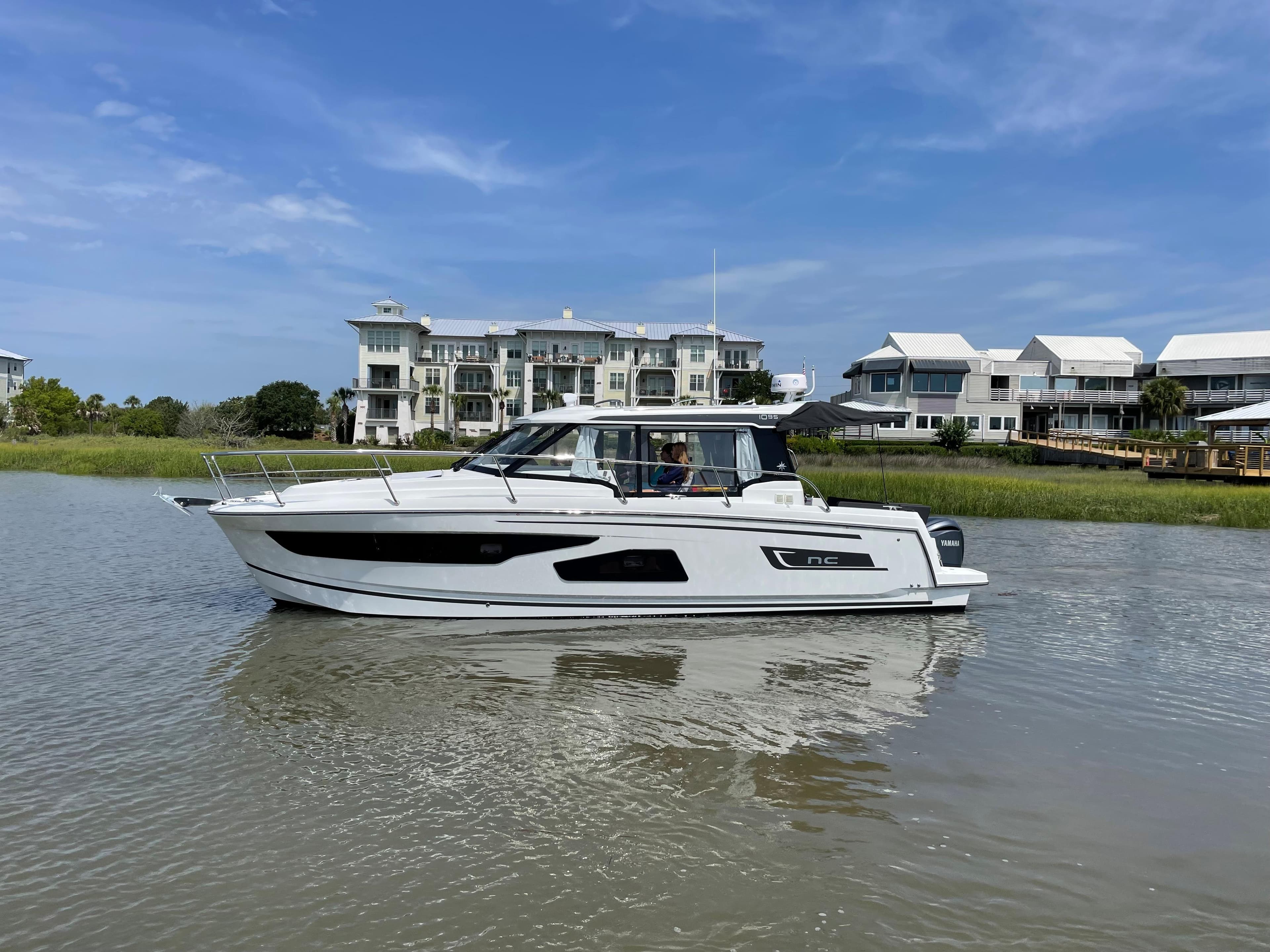 2024 Jeanneau NC 1095 boat cruising near waterfront homes.
