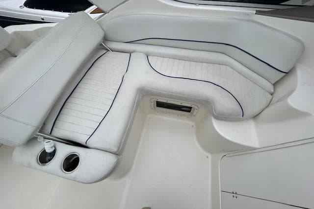 2003 Bayliner 285 boat interior with white cushioned seating and cup holders.
