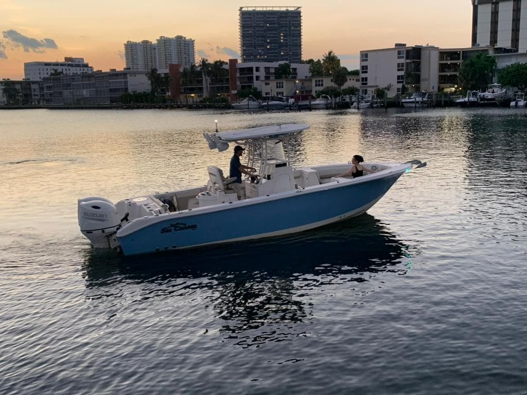 2019 Sea Chaser 27 HFC boat on calm water at sunset, urban skyline background.