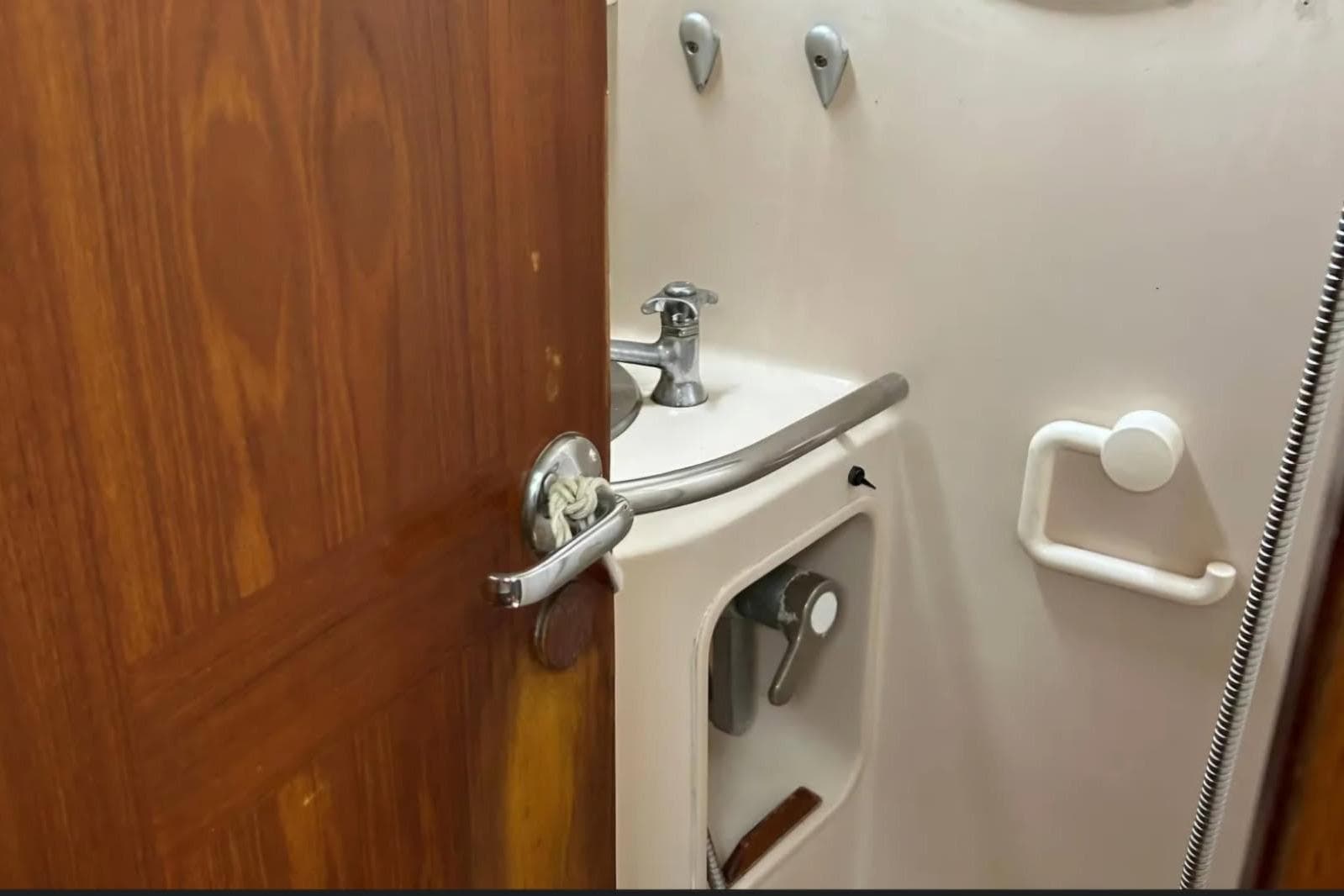 Interior of 1991 Beneteau Oceanis 50 yacht bathroom with sink and wooden door.