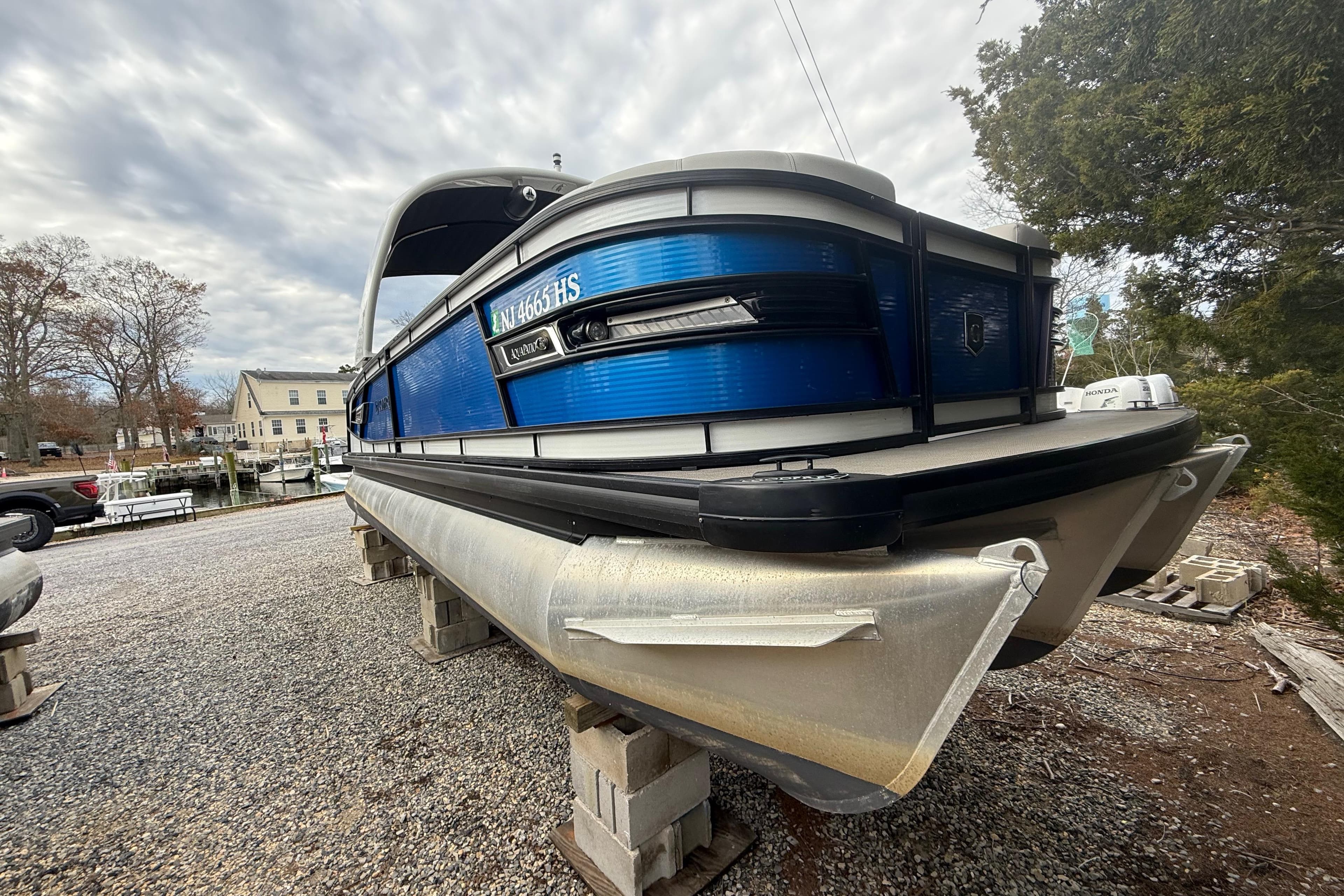 2023 Godfrey AquaPatio 255 ULC pontoon boat on dry dock, cloudy sky background.