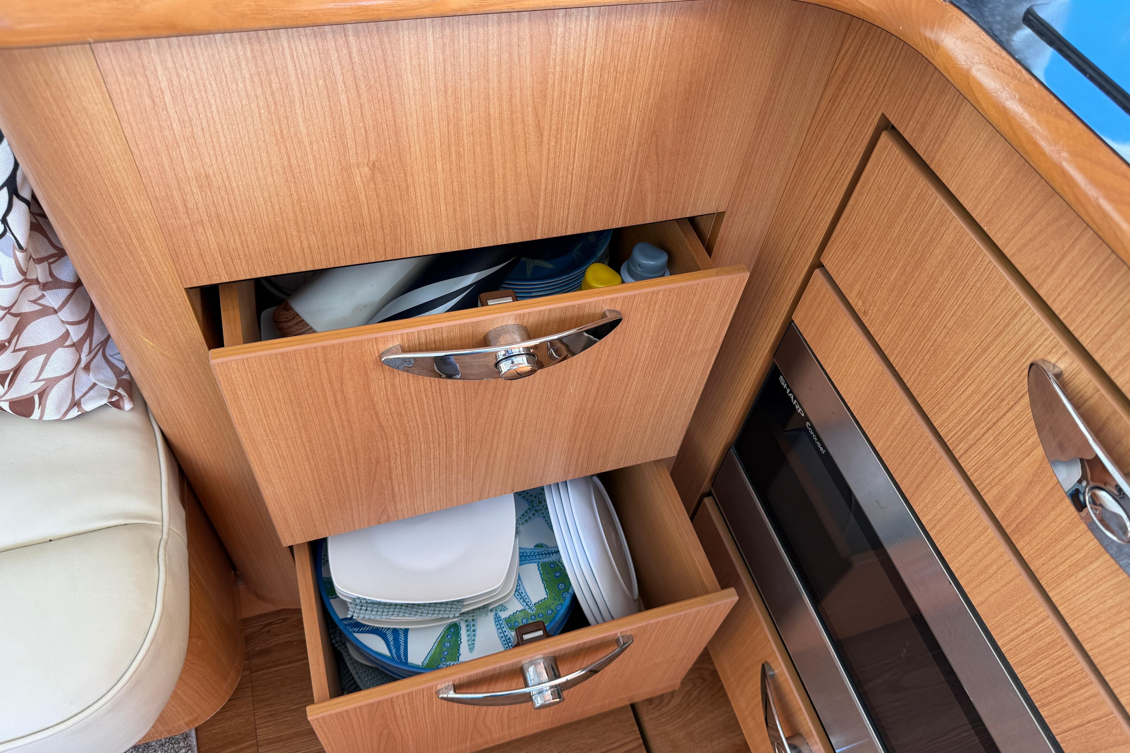 Wooden kitchen drawers in a 2013 Greenline 33 boat, storing plates and supplies.