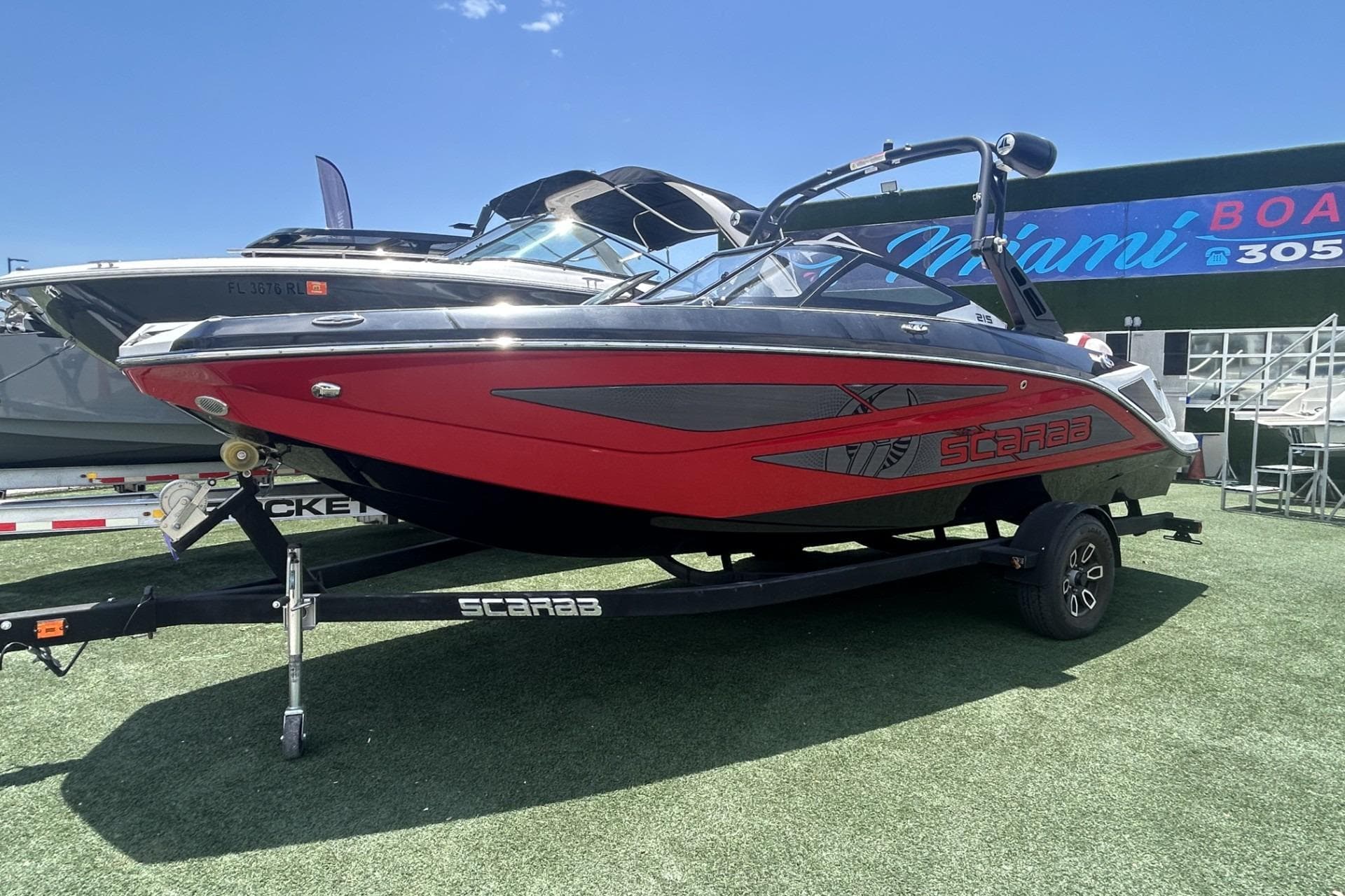 2023 Scarab 215 ID boat in red and black on display at Miami Boat Show.