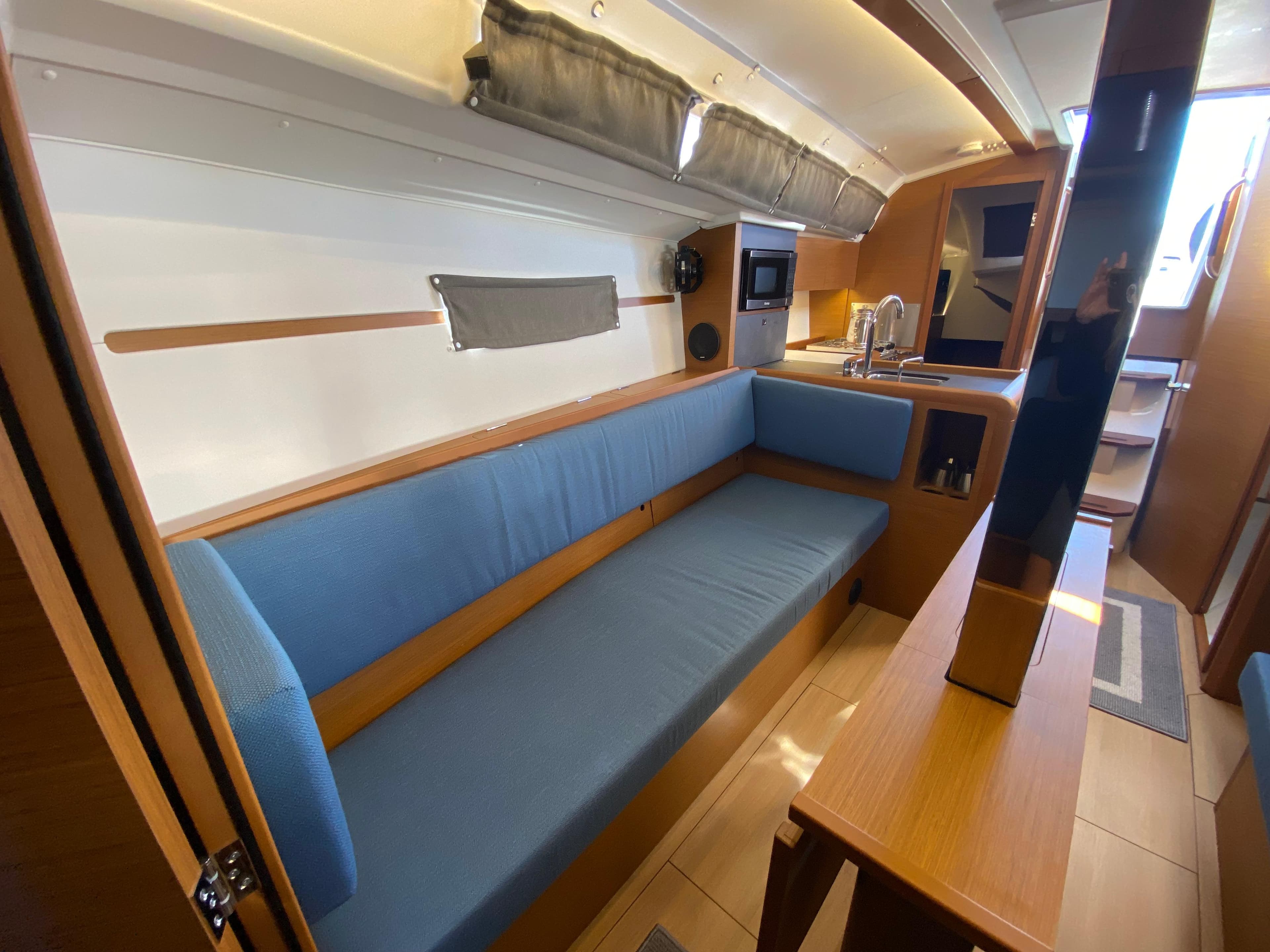 Interior of 2023 Jeanneau Sun Odyssey 349 sailboat with blue seating and modern kitchen.