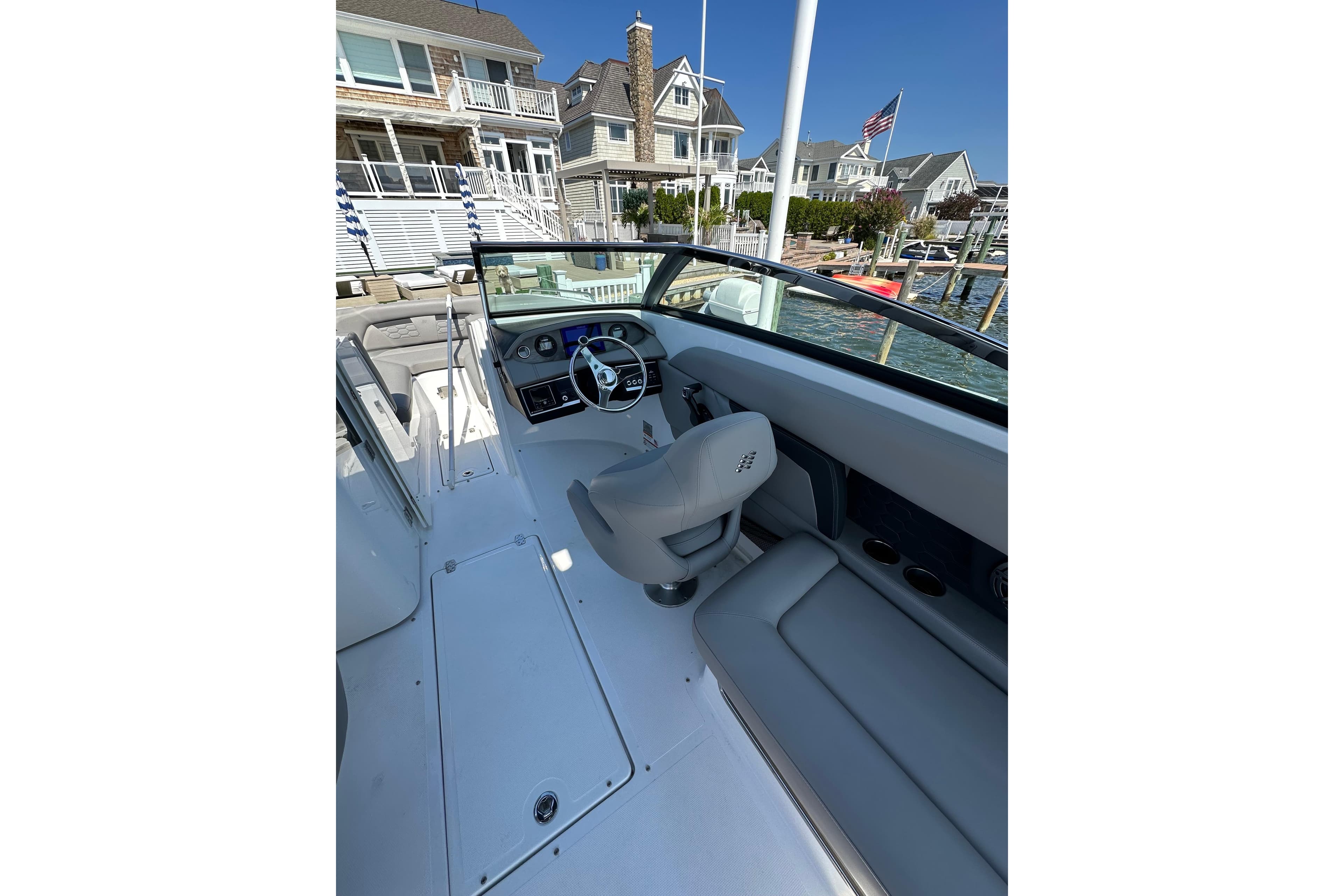 2022 Four Winns HD8 OB boat interior with steering wheel, docked near waterfront homes.