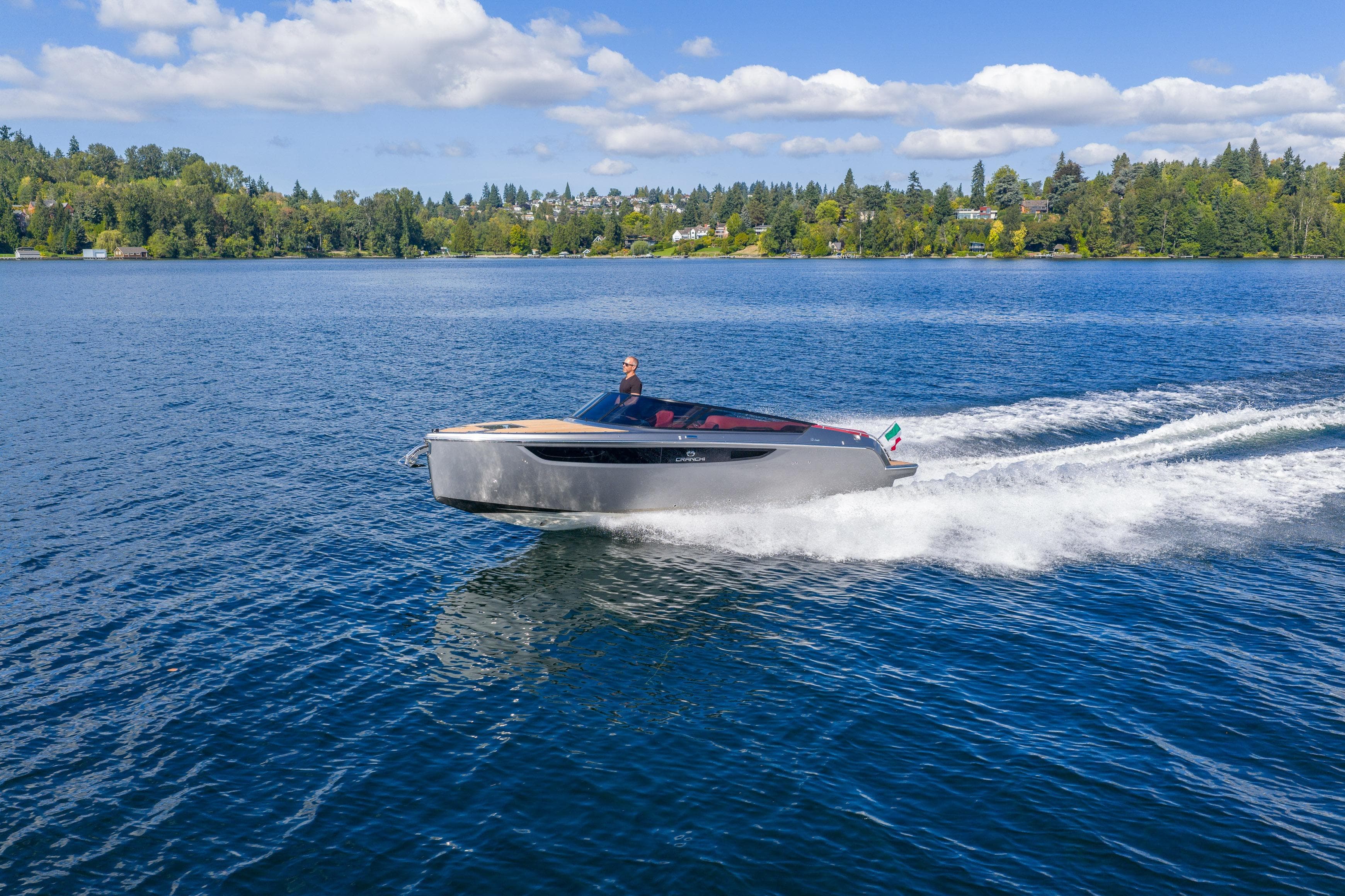 2026 Cranchi E26 Classic cruising on a serene lake under a clear blue sky.