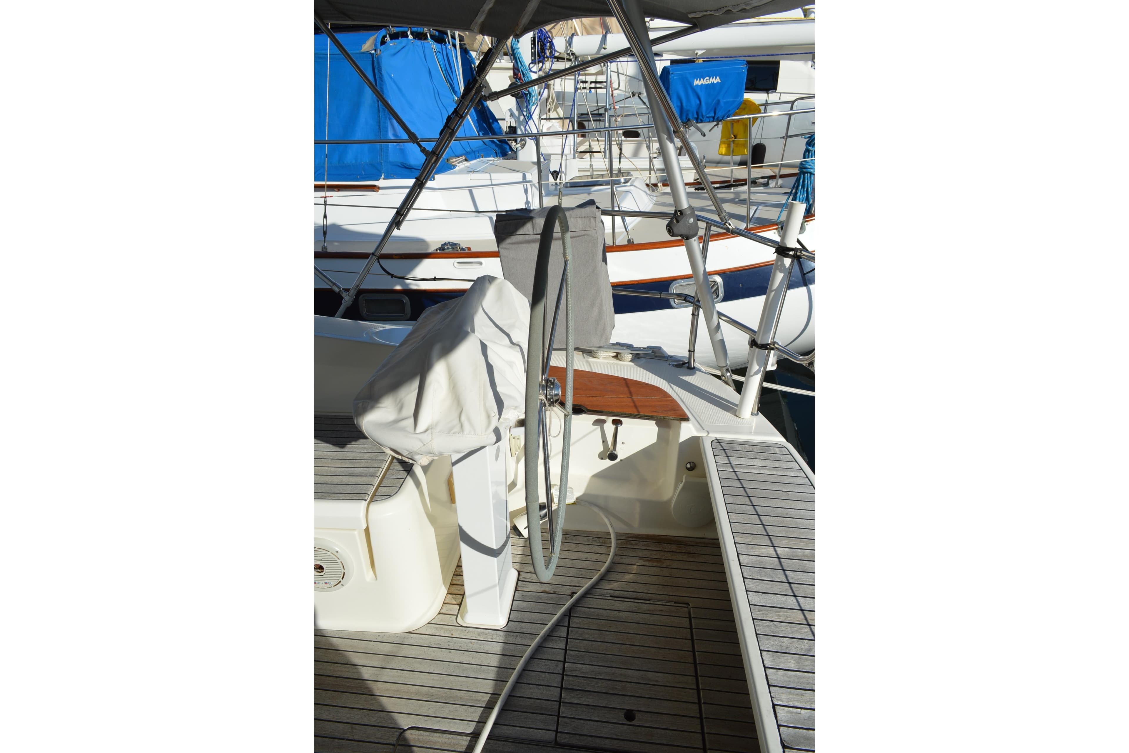 Sailboat cockpit of 2011 Bavaria 45 with covered steering wheel and wooden deck.
