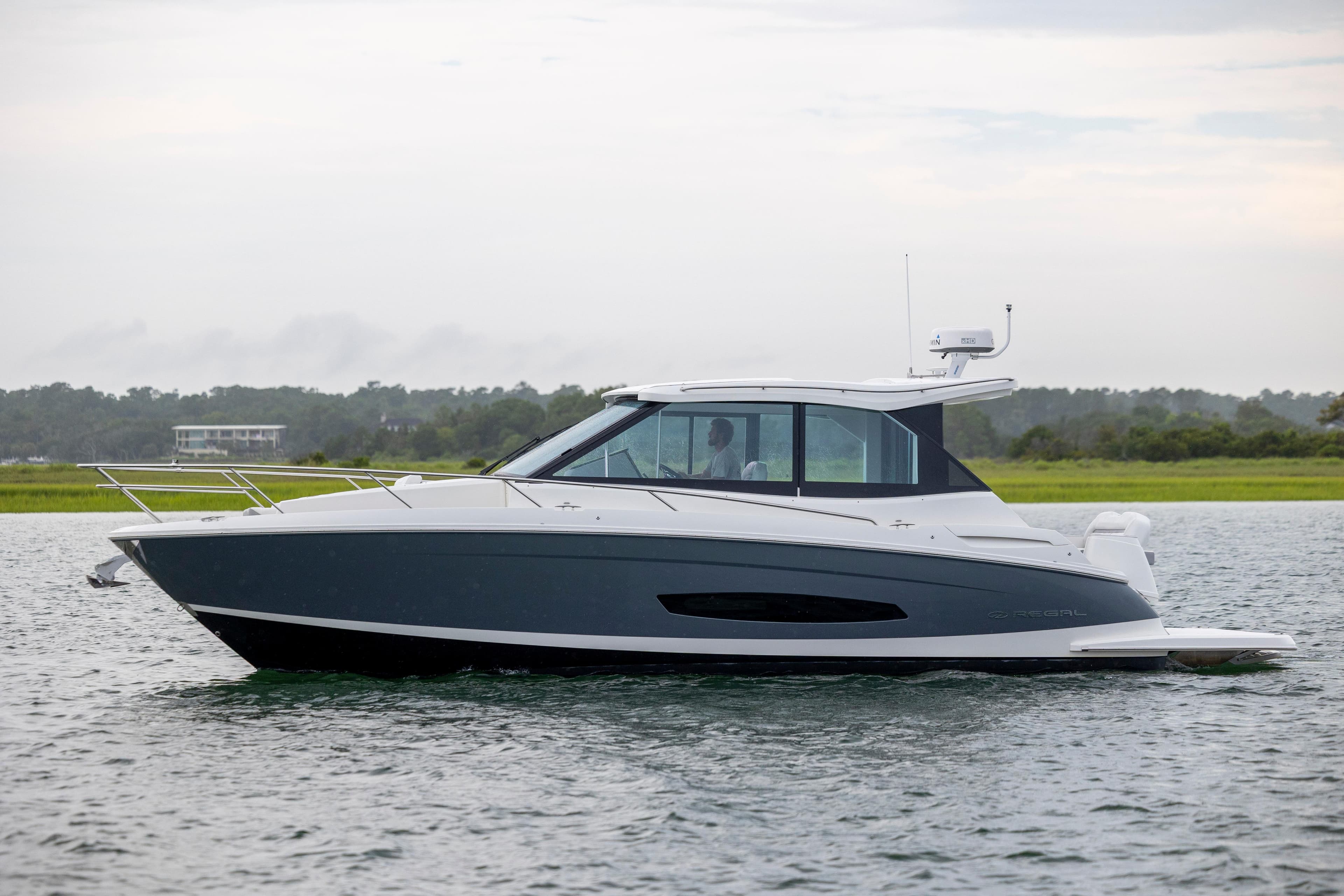 2022 Regal 36 Grande Coupe cruising on calm waters, side view.