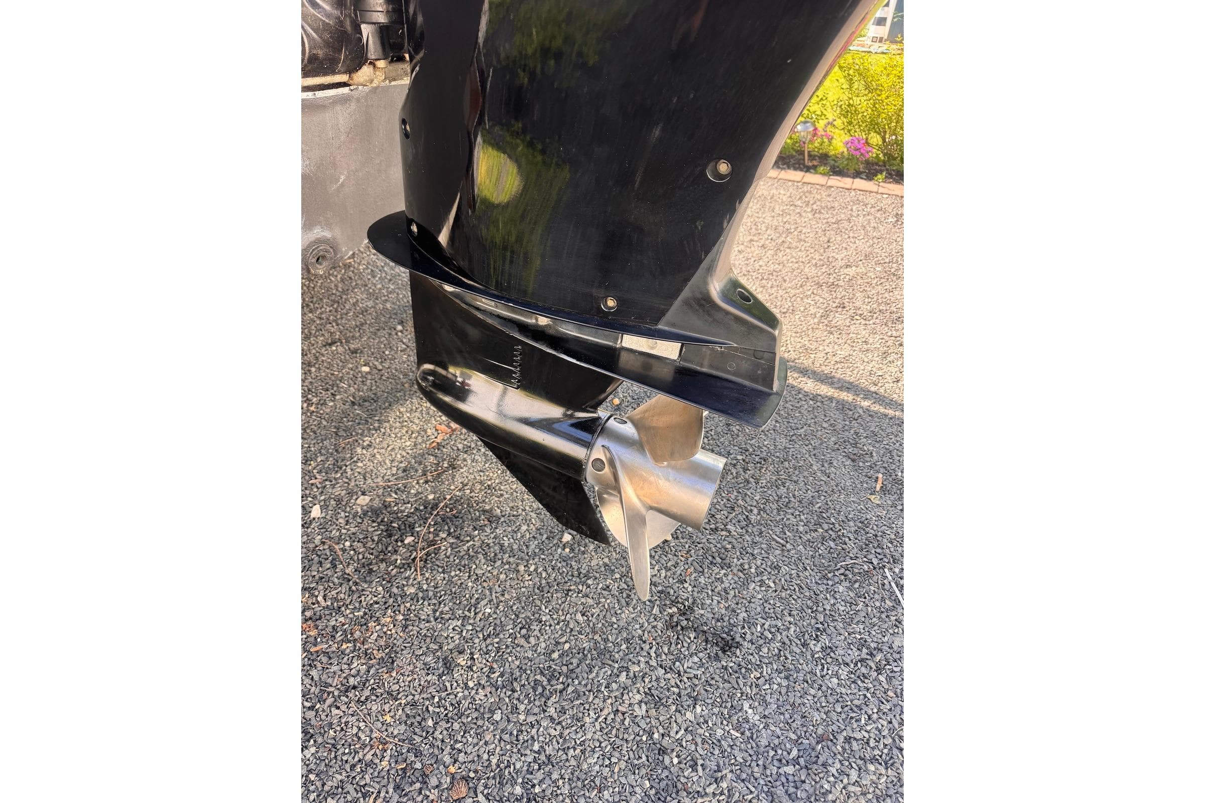 Outboard motor propeller of a 2006 Sea Pro 238 Walk Around boat on gravel.
