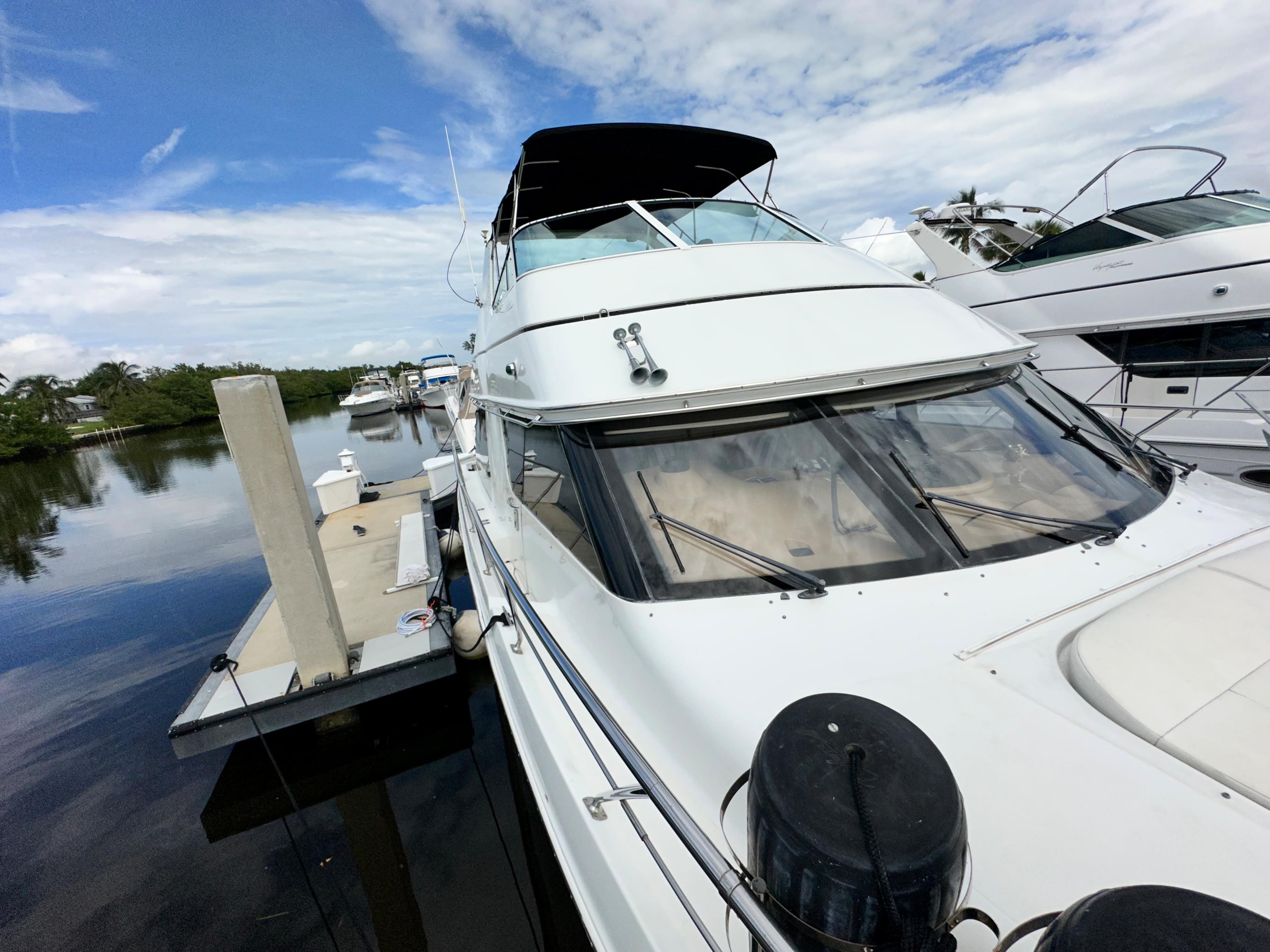 1999 Carver 450 Pilothouse yacht docked at marina under blue sky.