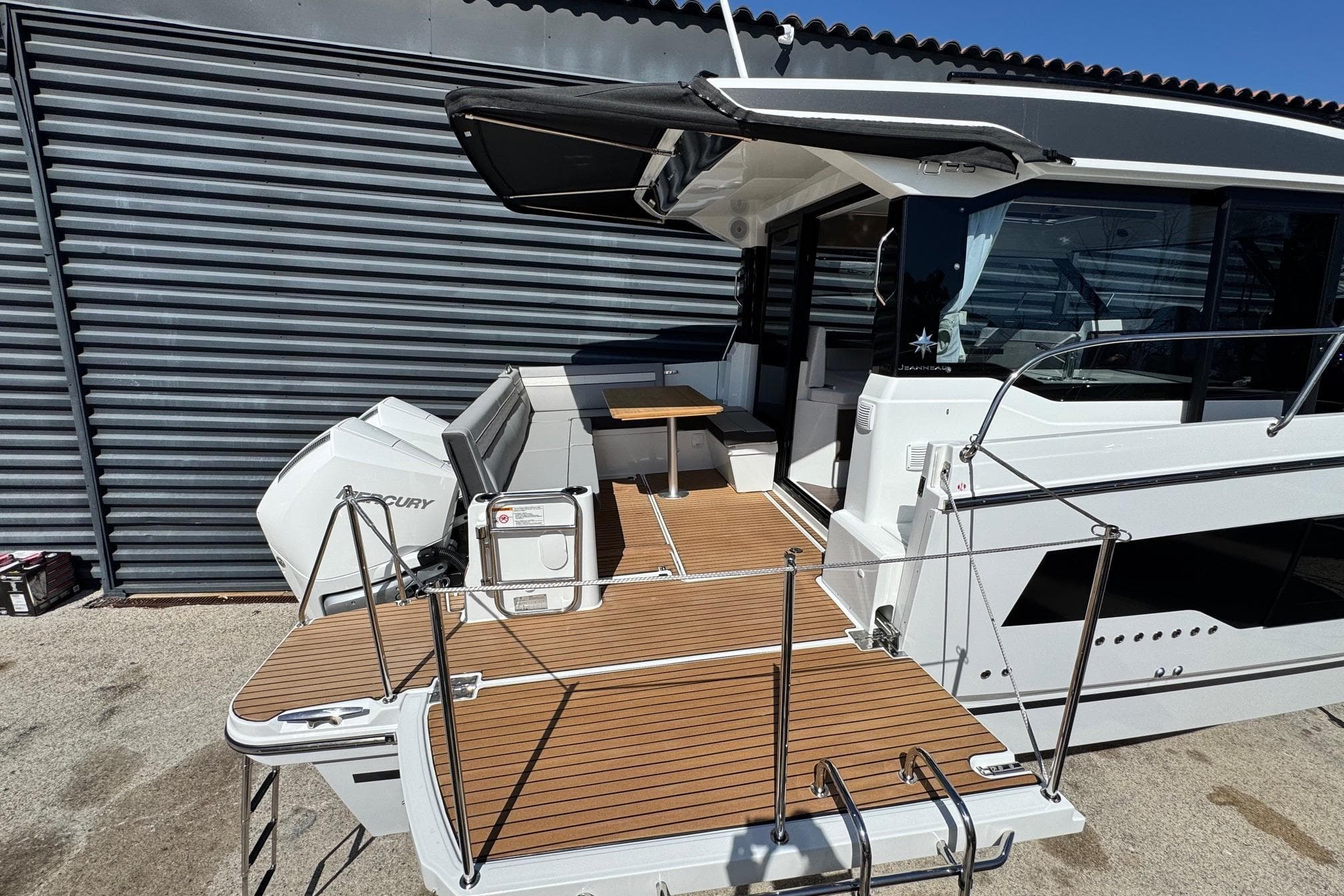 2026 Jeanneau Merry Fisher 1095 boat with Mercury engine, docked, featuring spacious deck and seating area.