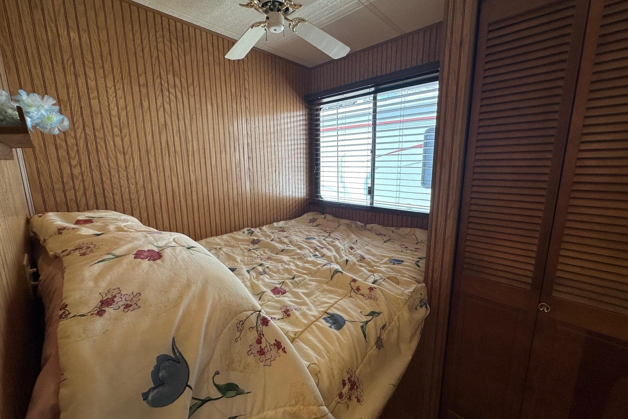 Cozy bedroom in 1993 Sumerset 14x65 houseboat with floral bedding and wood paneling.