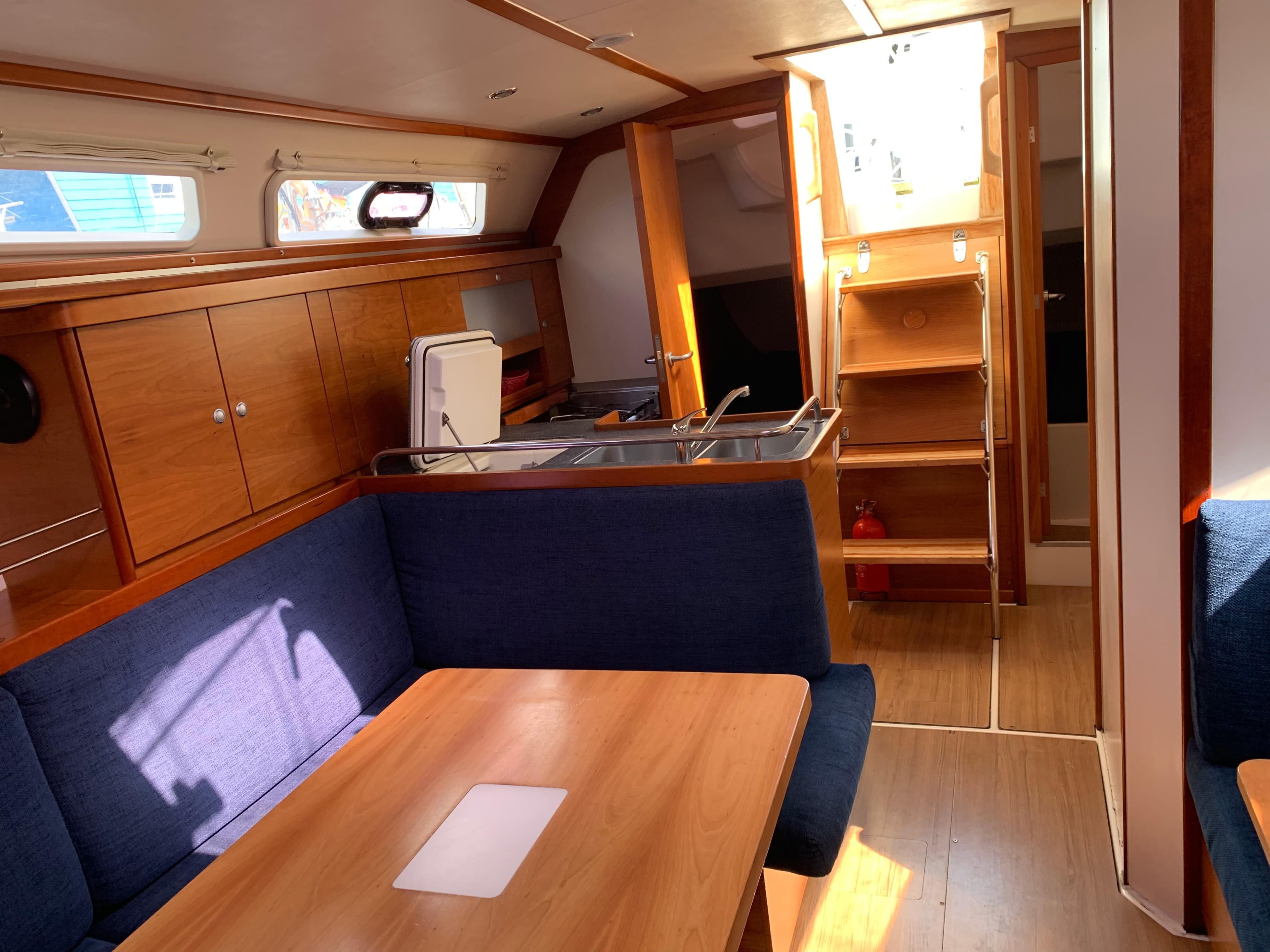 Interior of 2009 Hanse 370 sailboat with wooden cabinetry and blue seating.