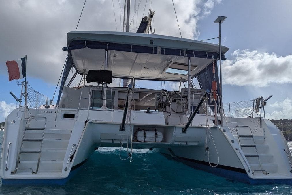 2008 Lagoon 420 catamaran on water, rear view, with clear sky background.