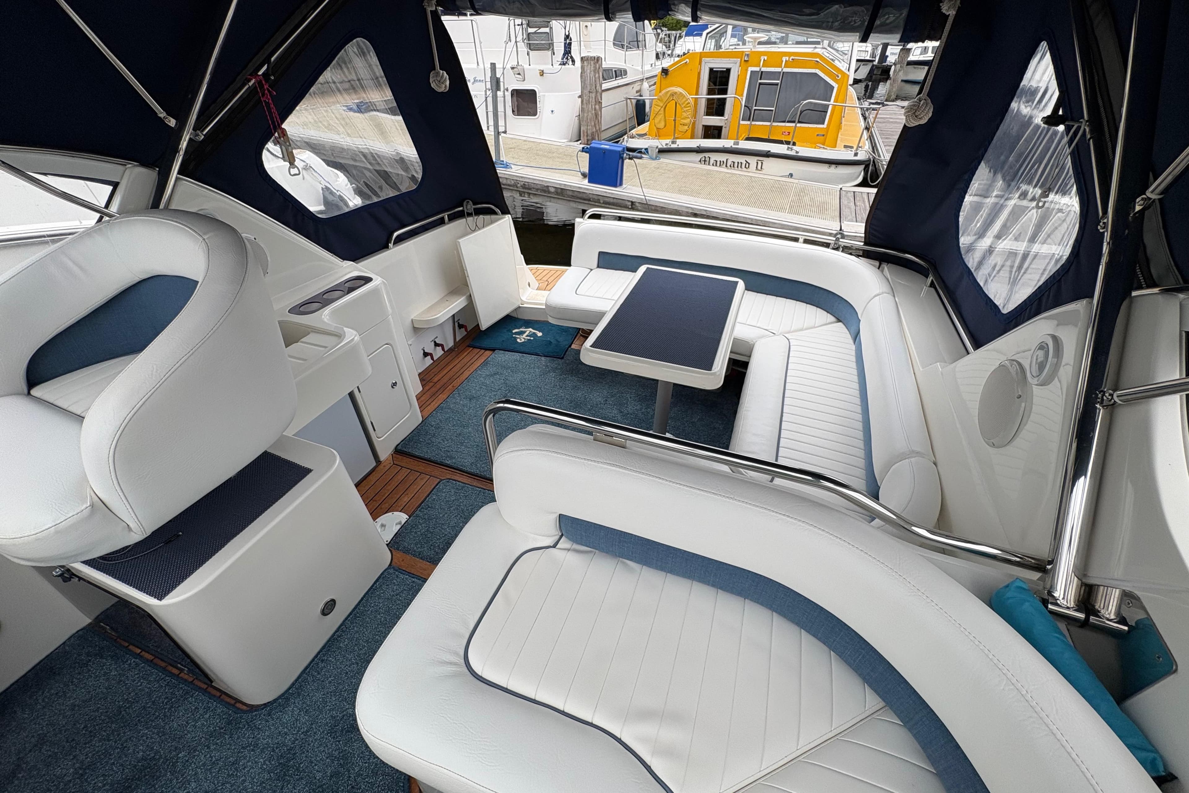 Interior of a 2002 Capriole 900 boat with white seating and a central table.