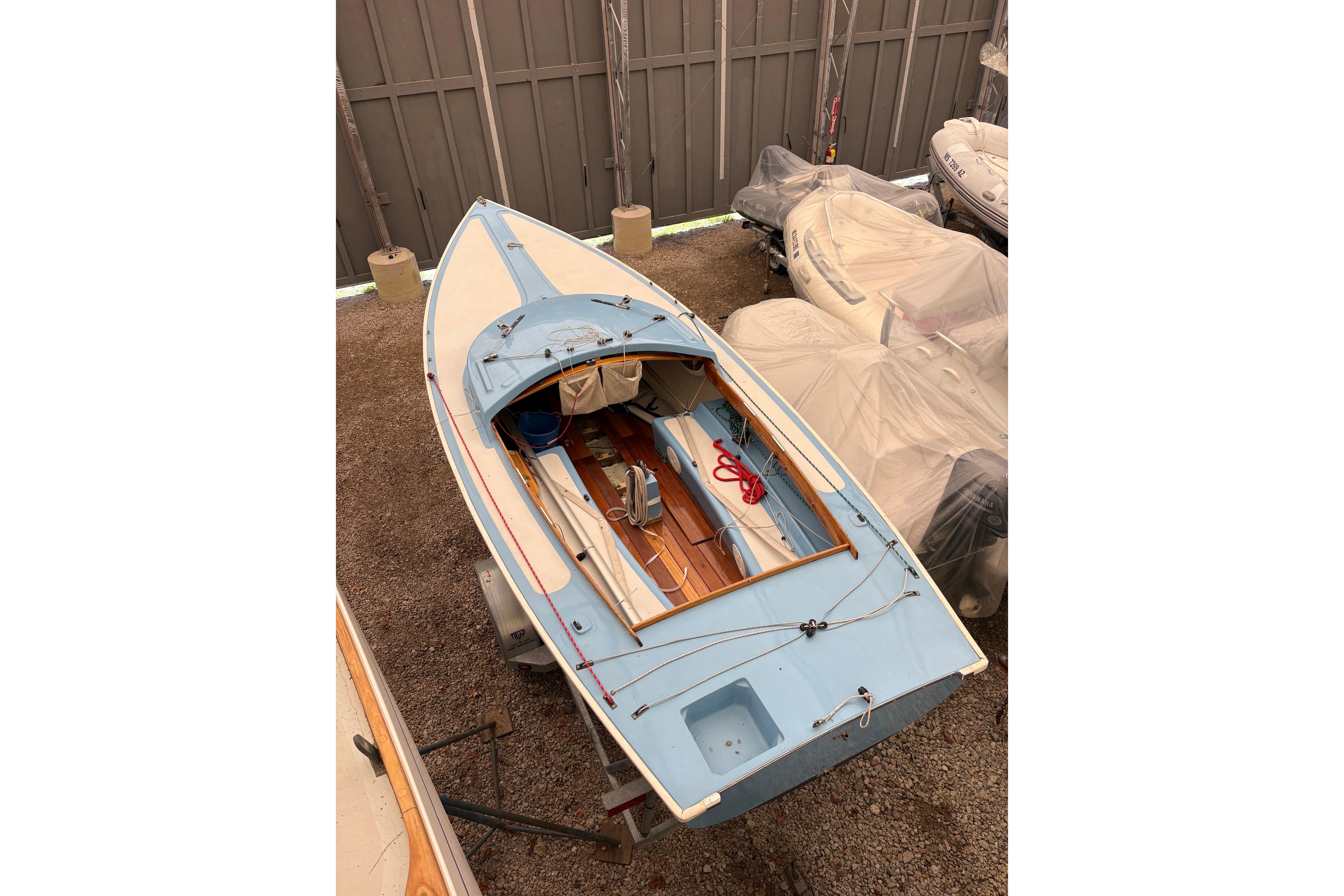 1971 Rhodes 19 sailboat in storage, featuring a blue and white design.