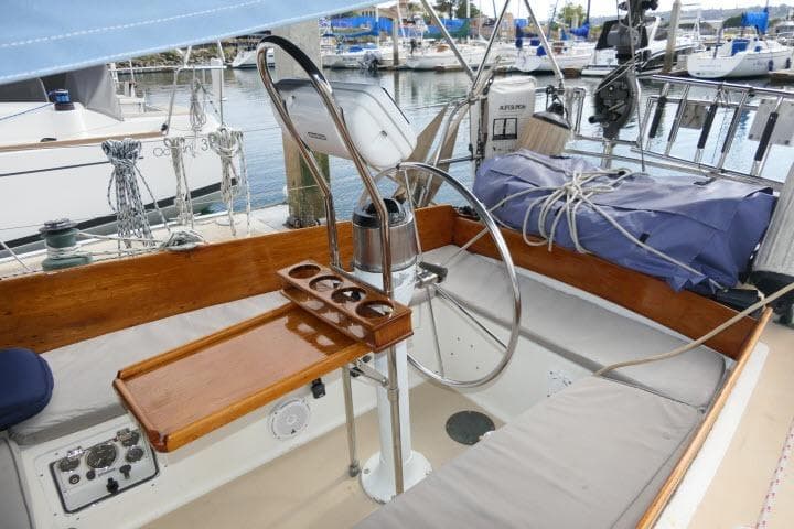 Cockpit of a 1982 Cape Dory 36 sailboat with wooden accents and steering wheel.