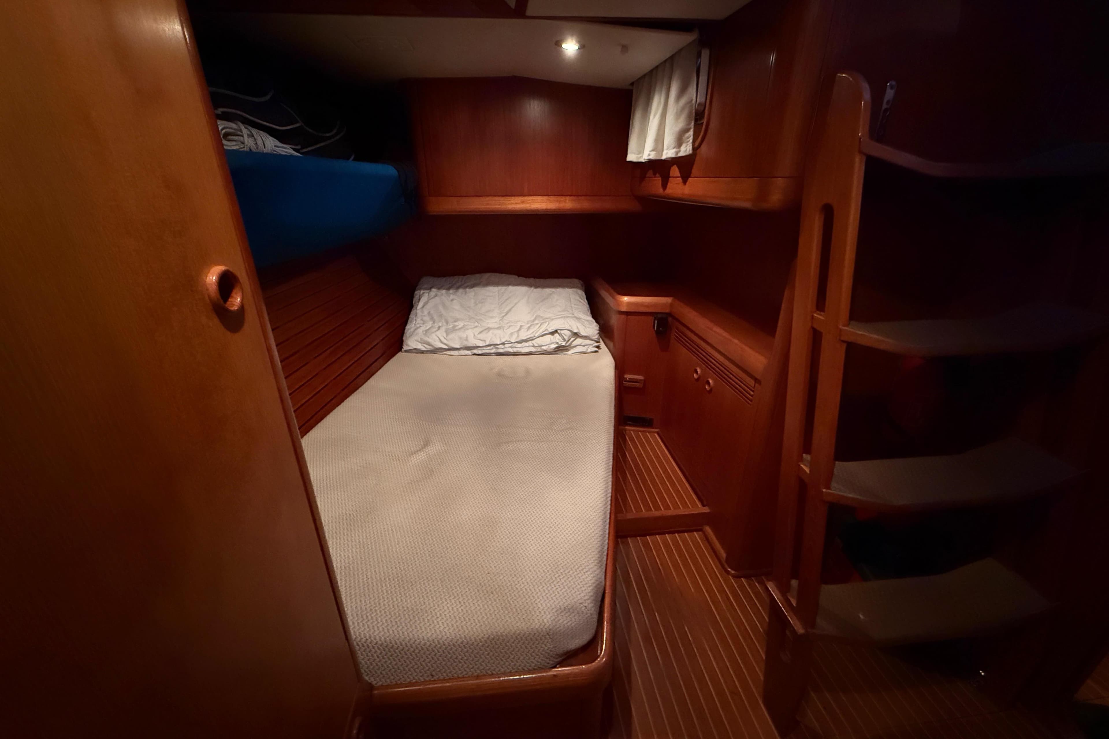 Cozy cabin interior of 1997 Nautor Swan 56R yacht with wooden finish and bedding.