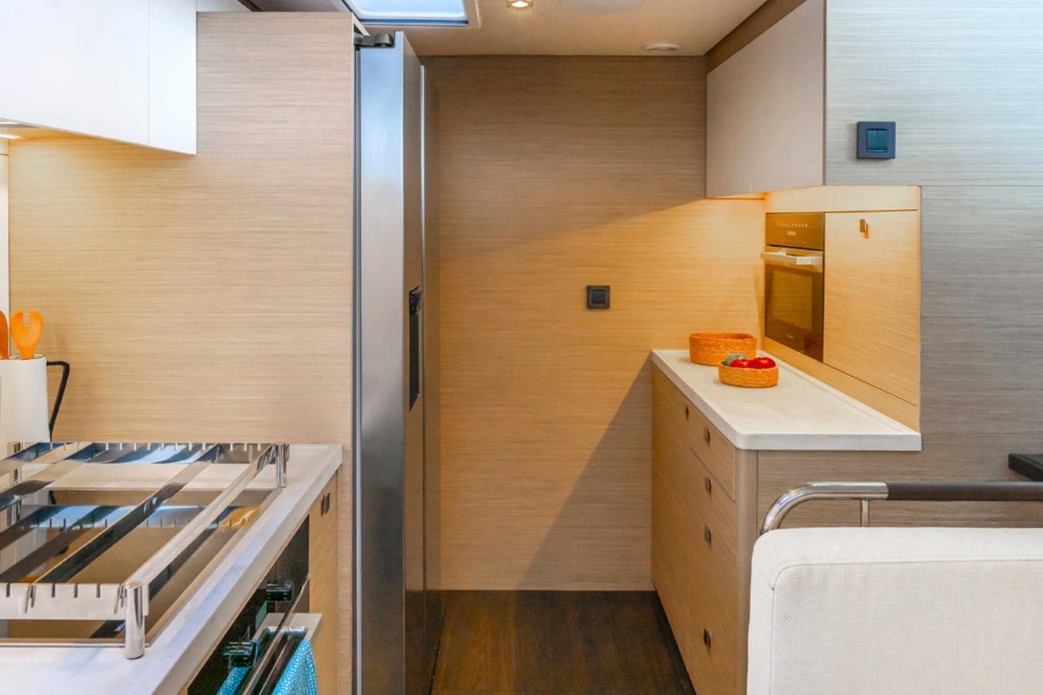 Modern kitchen interior of 2026 Lagoon 60 yacht with sleek appliances and wooden cabinetry.
