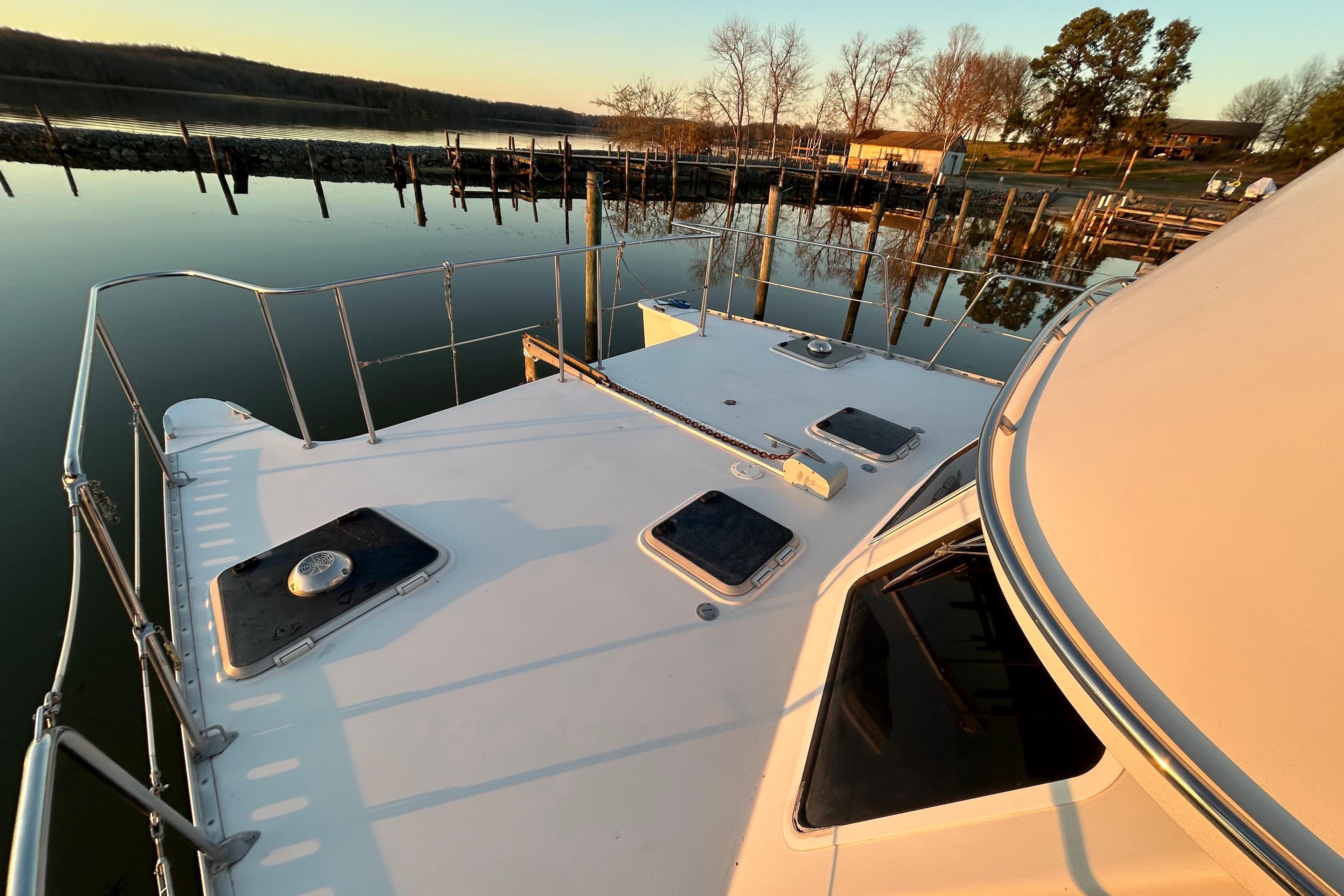 2004 PDQ 34 Power Catamaran docked at serene waterfront during sunset.