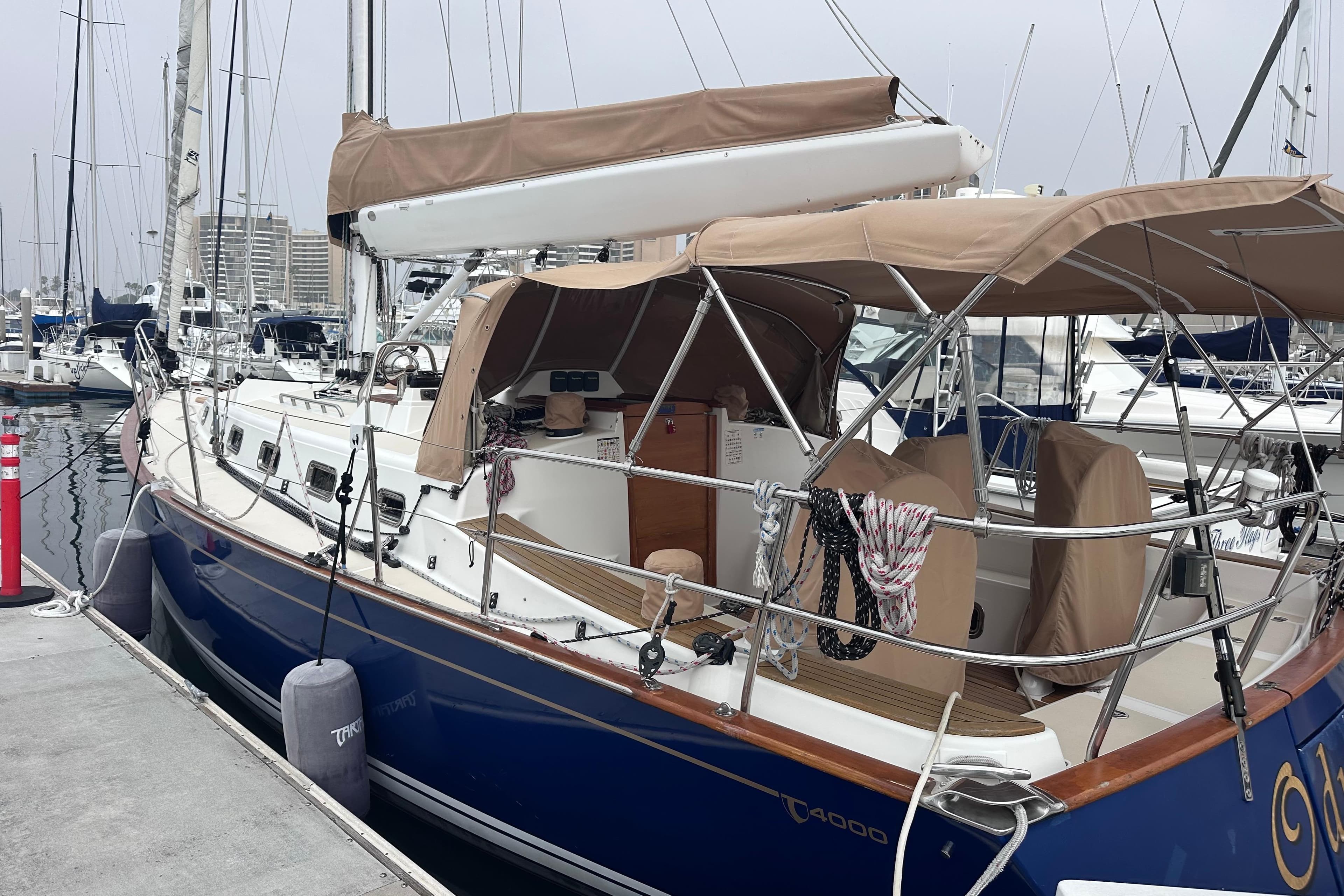 Sailboat docked at marina, Tartan 4000 model, 2016, with beige canopy and blue hull.