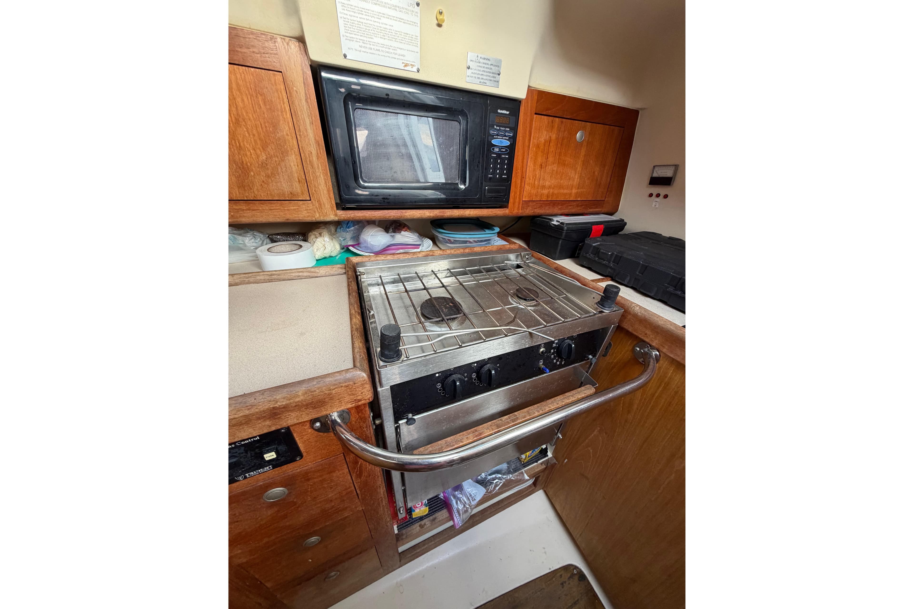 Compact kitchen area in a 2000 Hunter 310 sailboat with stove and microwave.