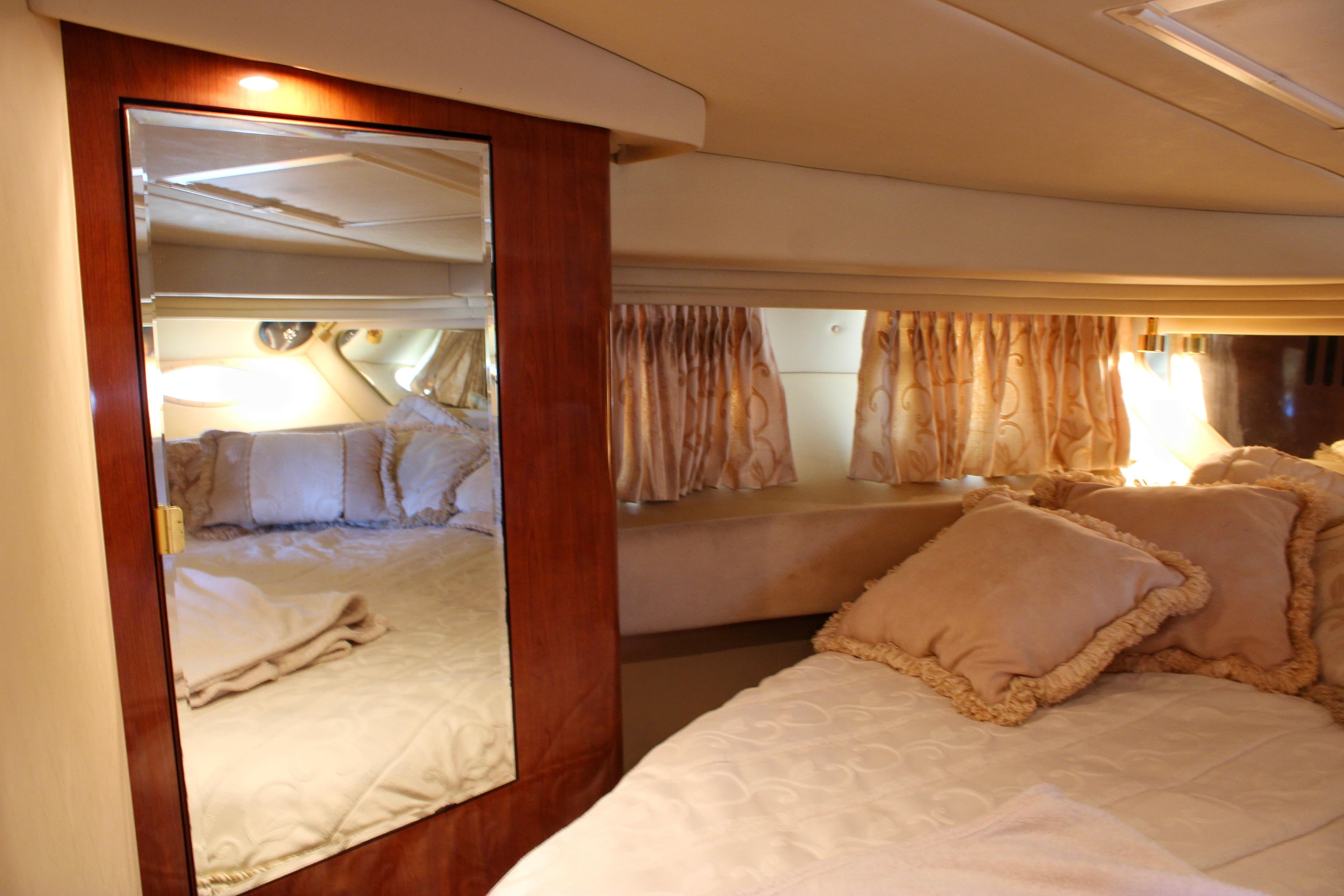 Luxurious cabin interior of 2003 Sea Ray 380 Sundancer with elegant bedding and mirrored closet.