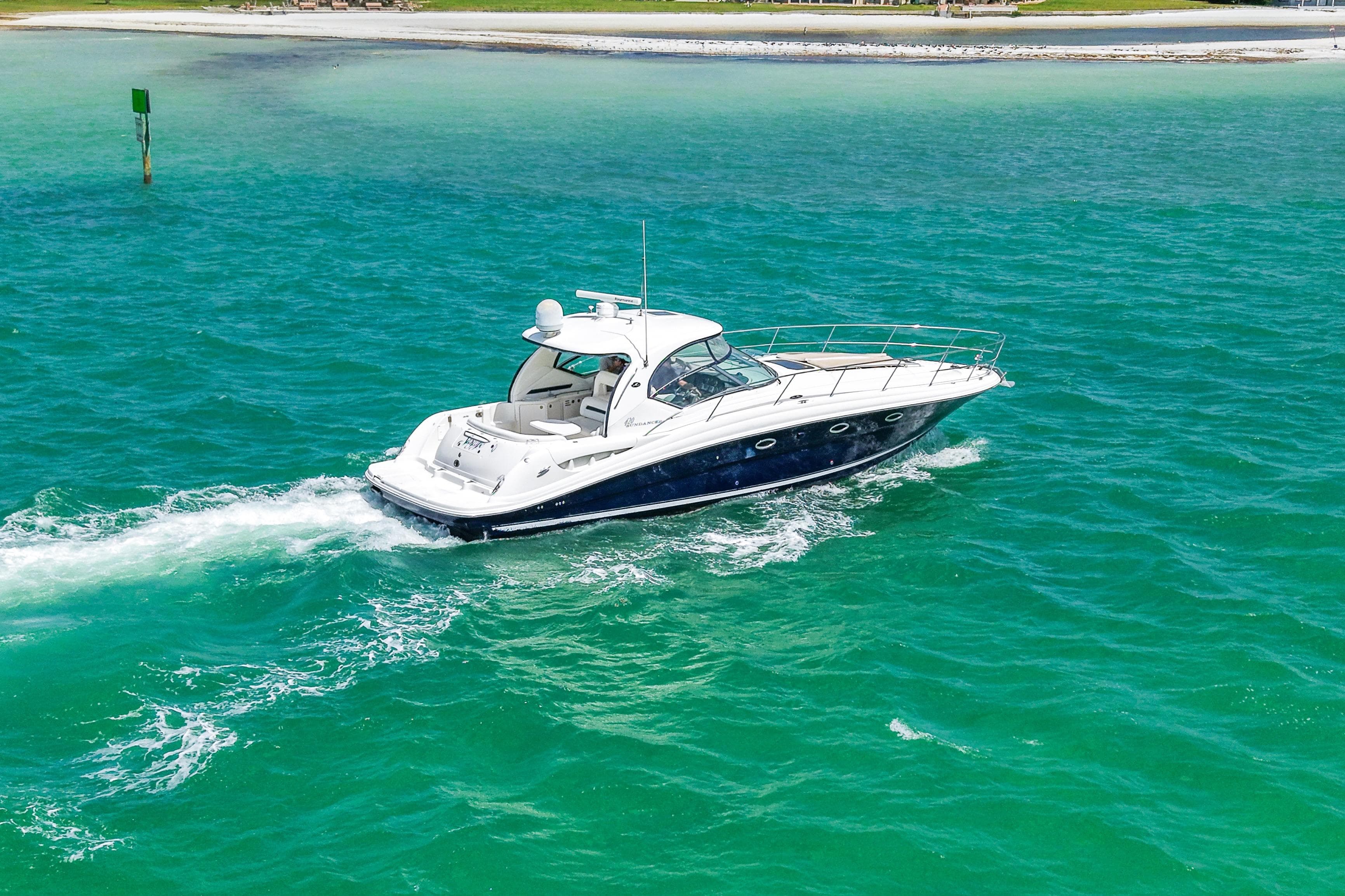 2004 Sea Ray 420 Sundancer cruising on turquoise waters near a sandy shoreline.
