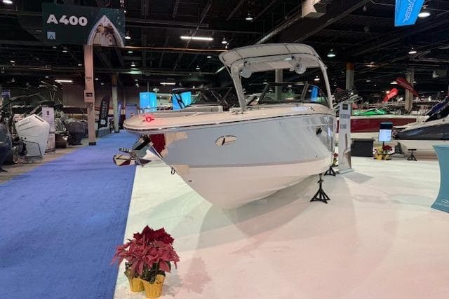 2026 Regal LS6 Surf boat displayed at an indoor exhibition with blue carpet.