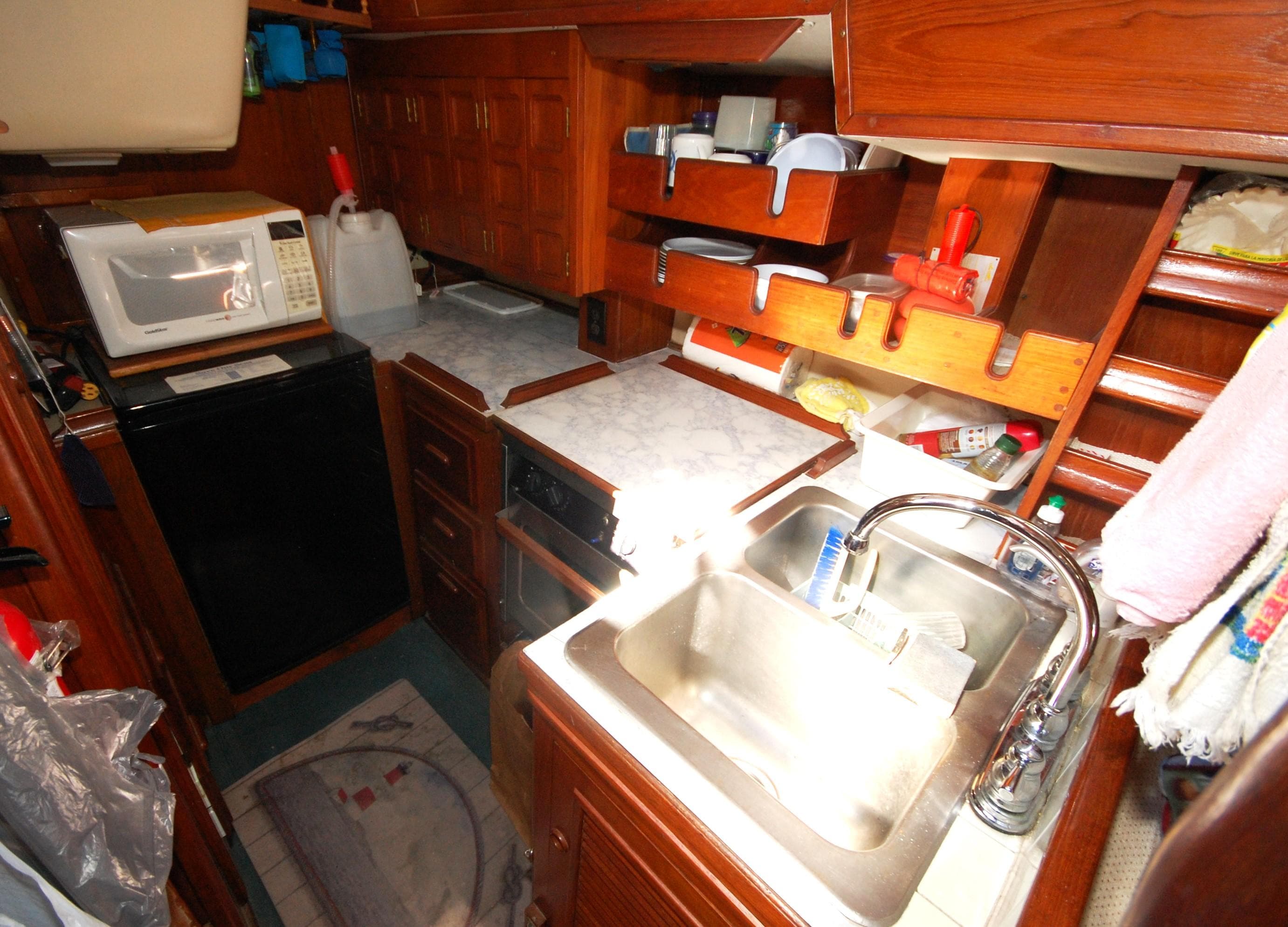 1981 Endeavour 40 yacht galley with sink, microwave, and wooden cabinetry.