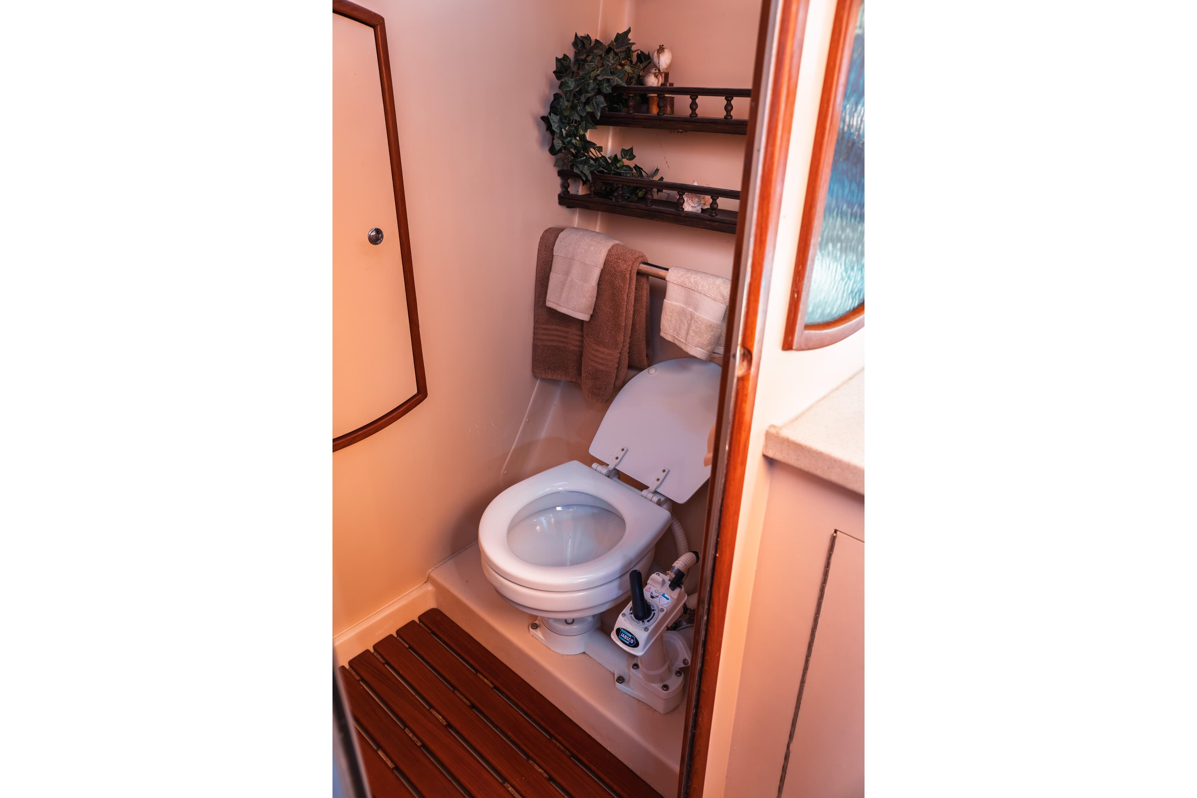Compact bathroom in 2003 Hunter 356 yacht with toilet, wooden floor, and shelves.