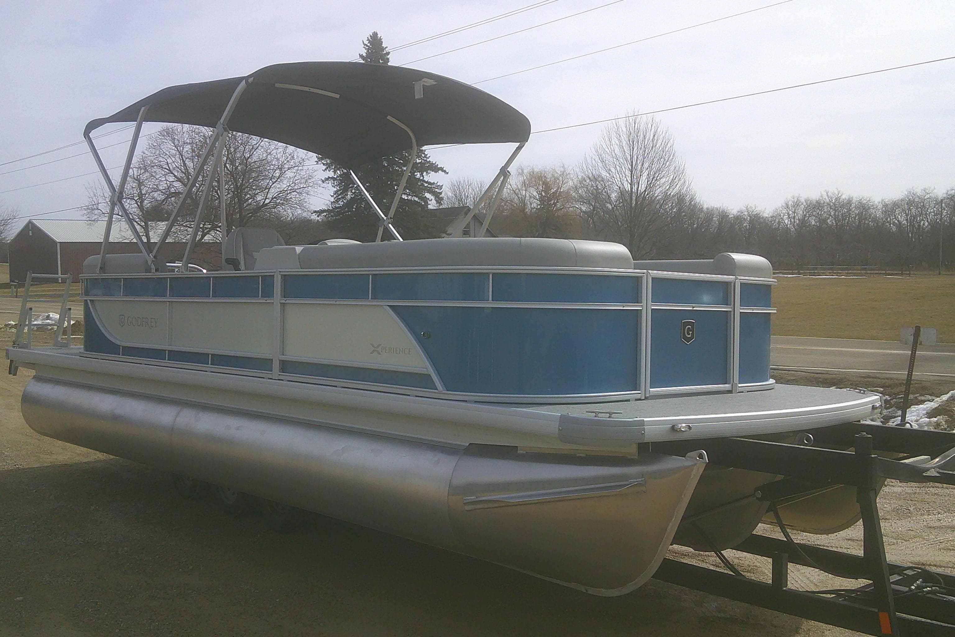2026 Godfrey EX 2286 SBX pontoon boat with canopy, parked on a trailer.
