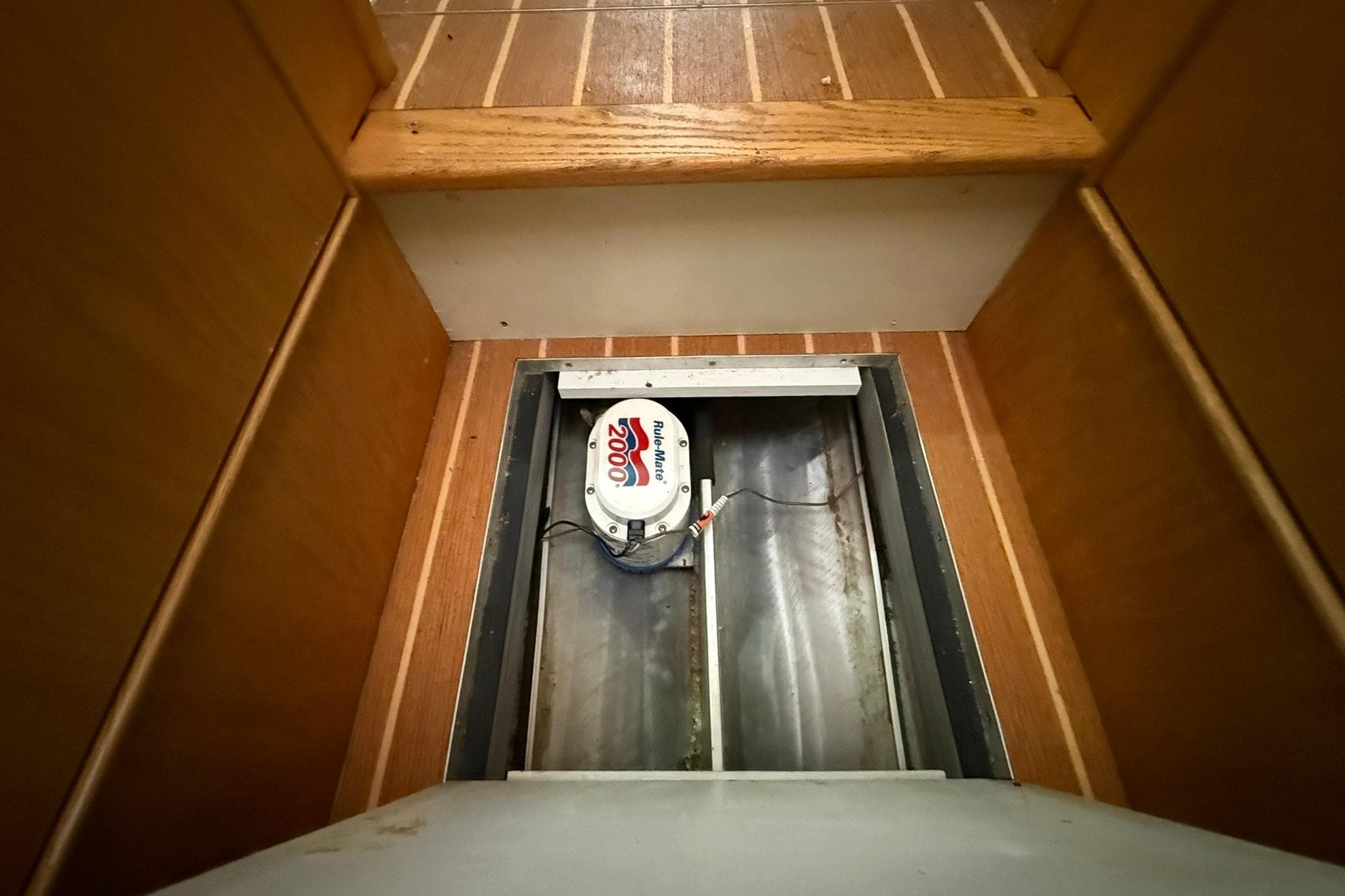 Bilge pump in 2013 Eco-Trawler 33, wooden flooring, open hatch view.