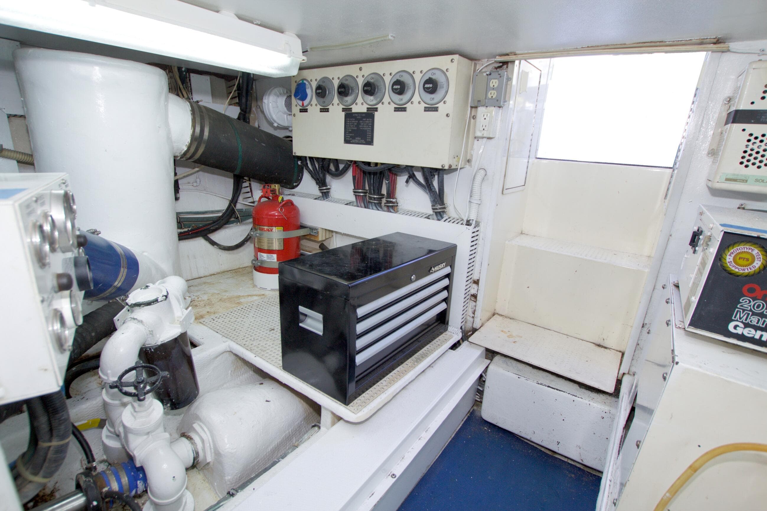 Engine room of 1990 Viking 53 Convertible yacht with control panel and fire extinguisher.