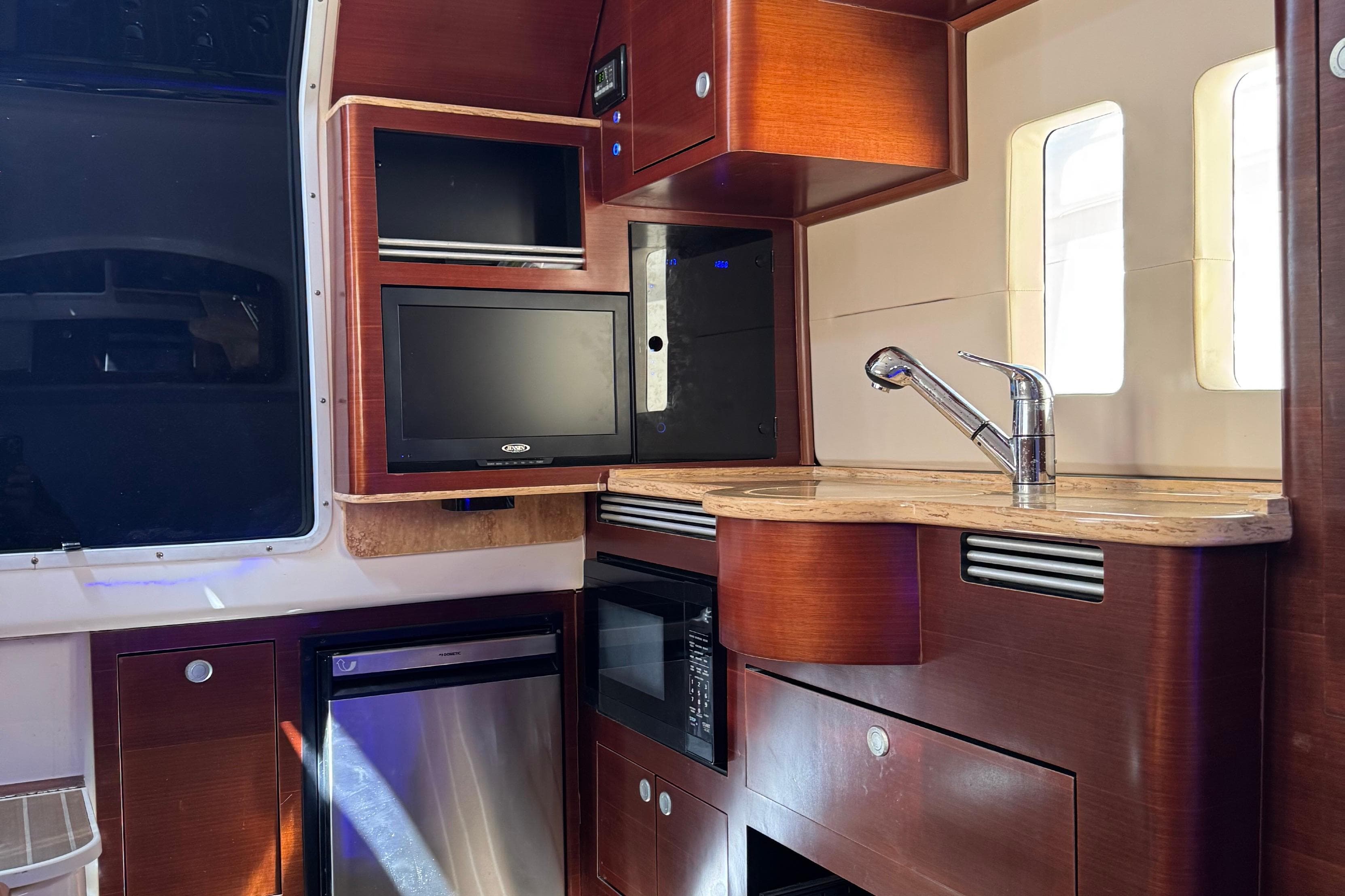 Interior of 2016 Edgewater 370CC boat with kitchenette, sink, and TV.