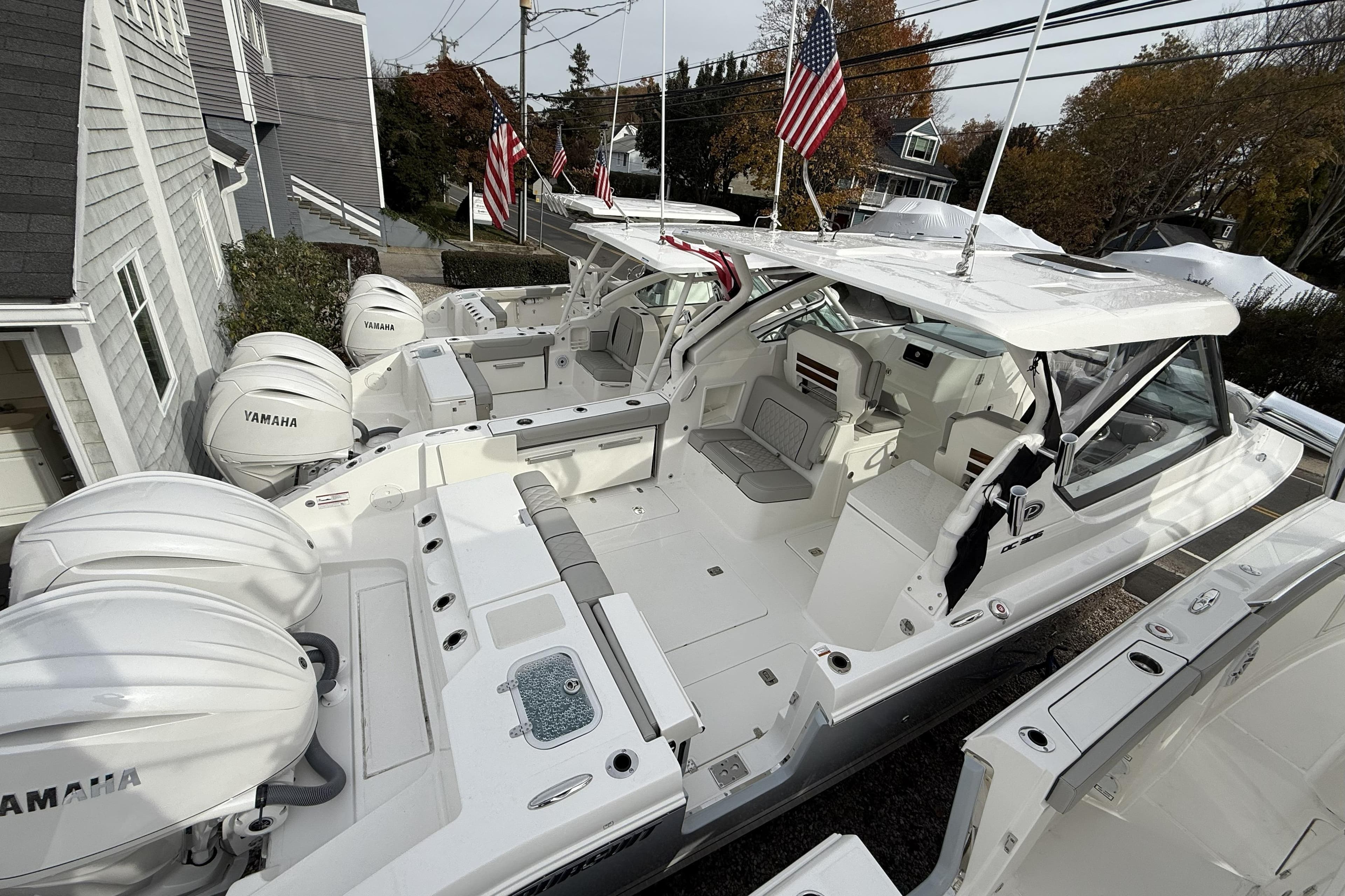 2026 Pursuit DC 306 Dual Console boat with Yamaha engines, docked near houses.
