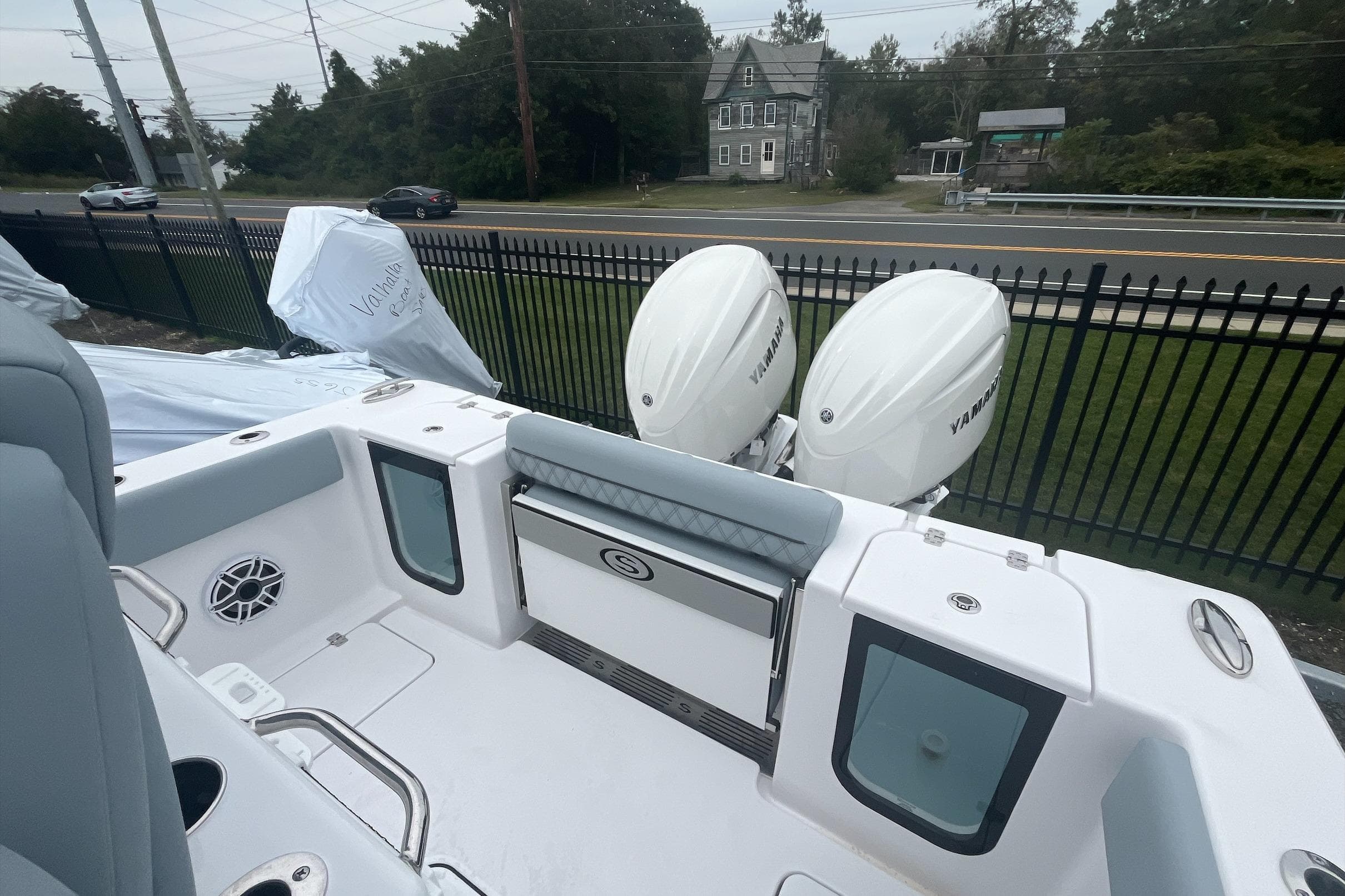 2026 Sportsman Open 262 Center Console boat with twin Yamaha engines, parked near a fence.