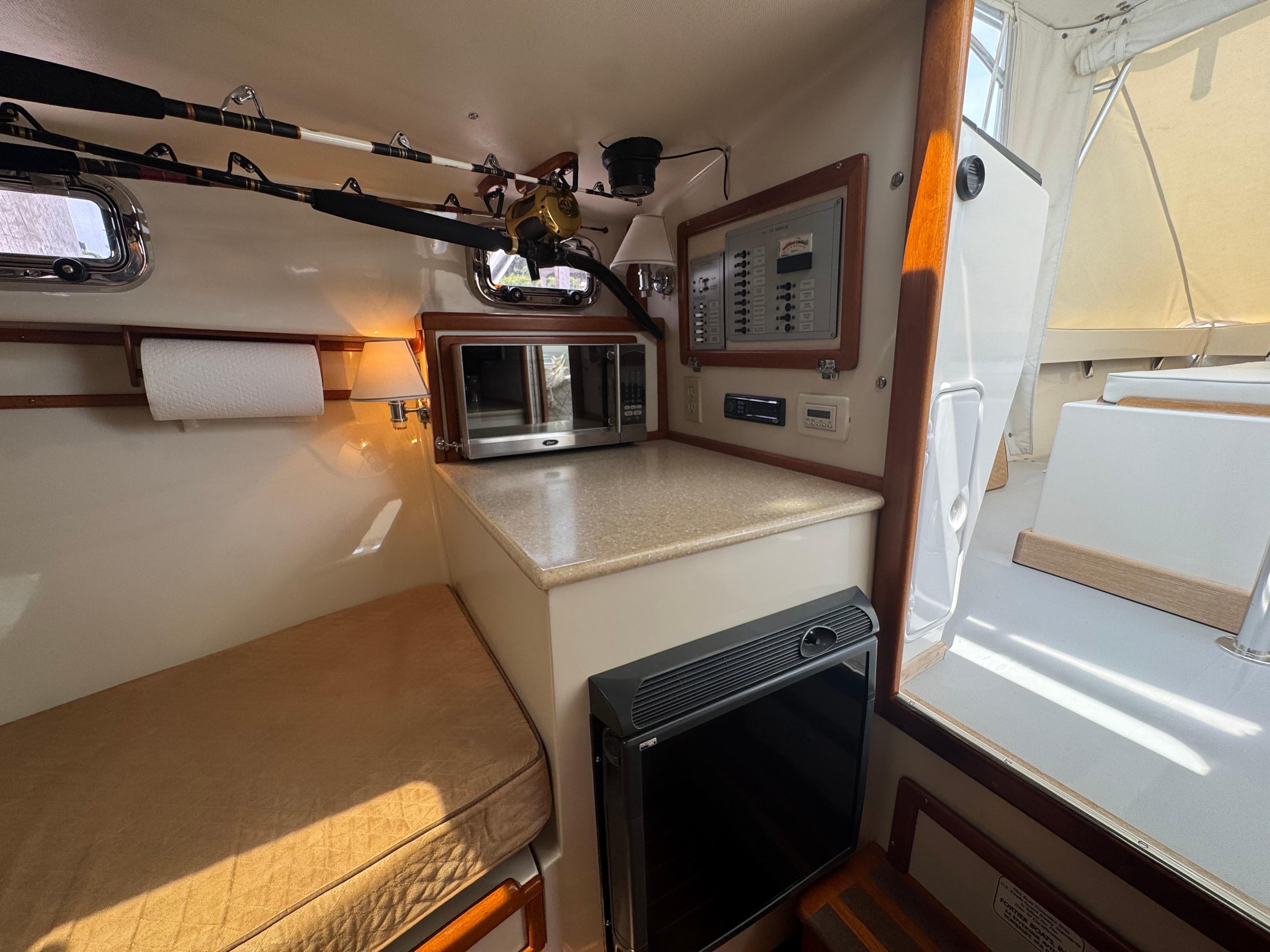 Interior of 2006 Fortier 26 boat with kitchenette, fishing rods, and control panel.